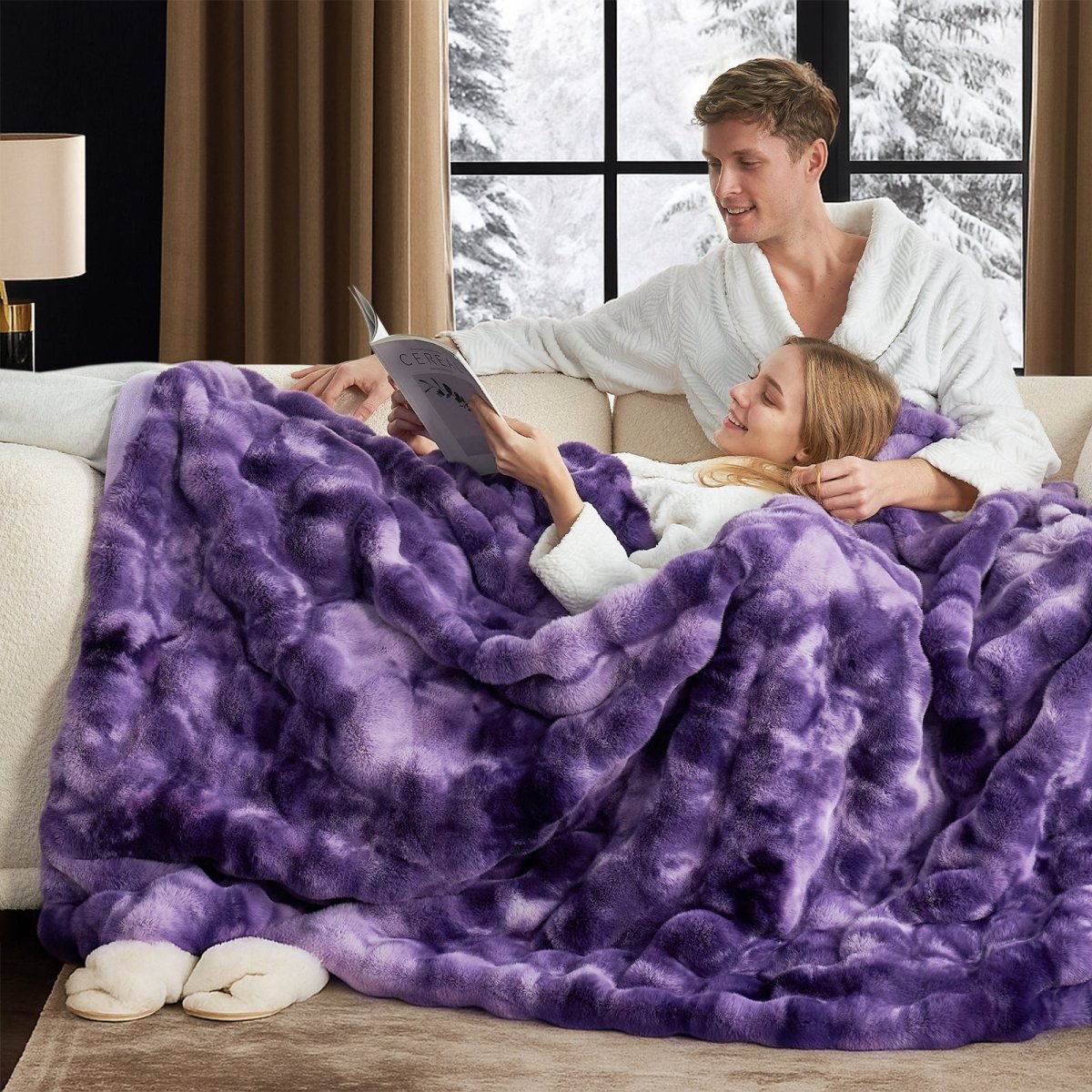 Man and woman reading a magazine while wearing Cozy Bliss tie-dye purple faux fur throw blanket with a snowy window view. #color_Tie-dye Purple