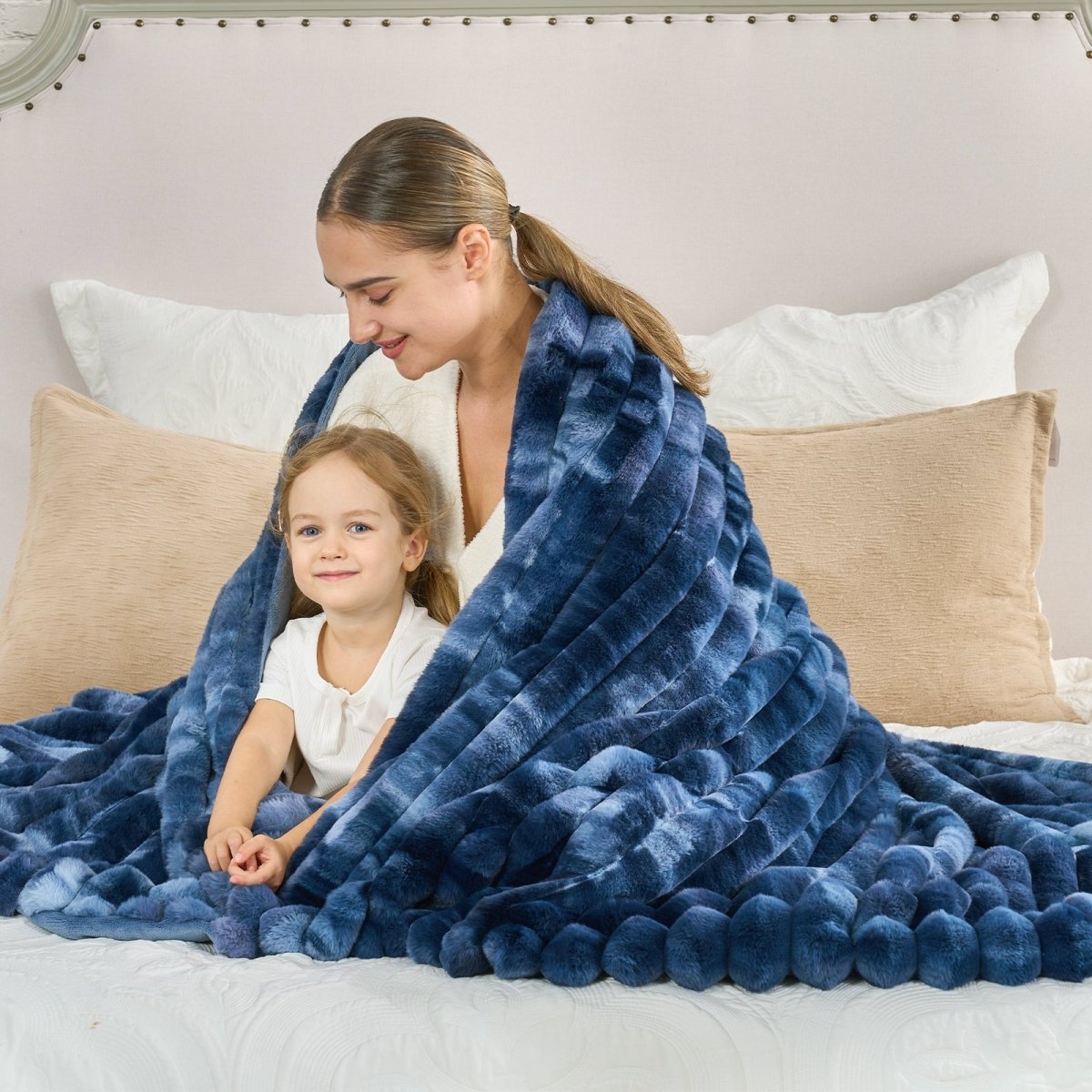 Woman and child under a blue blanket on a bed with beige pillows. #color_Tie-dye Blue