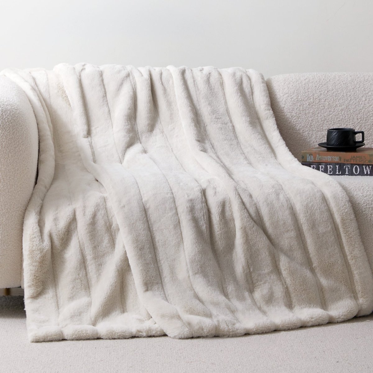 Cozy Bliss sheared faux fur throw blanket draped over a sofa, showcasing elegant ribbed texture #color_Ivory