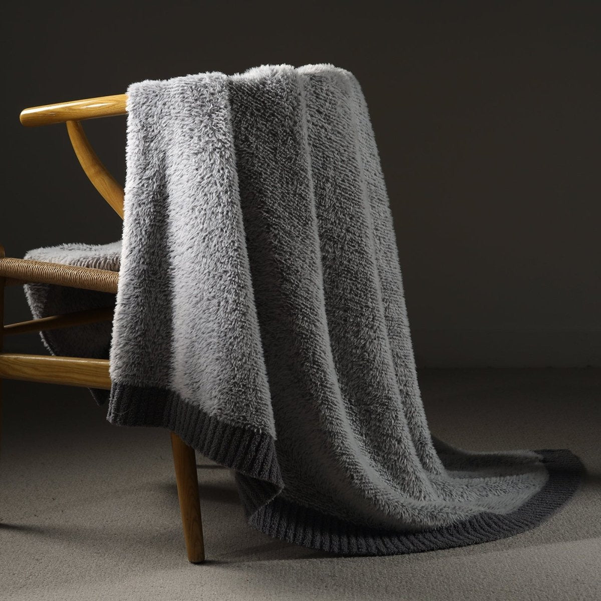 Faux Mink Feather Knit Throw Blanket in Grey draped over a chair, showcasing soft faux mink texture and elegant knit design. #color_Grey