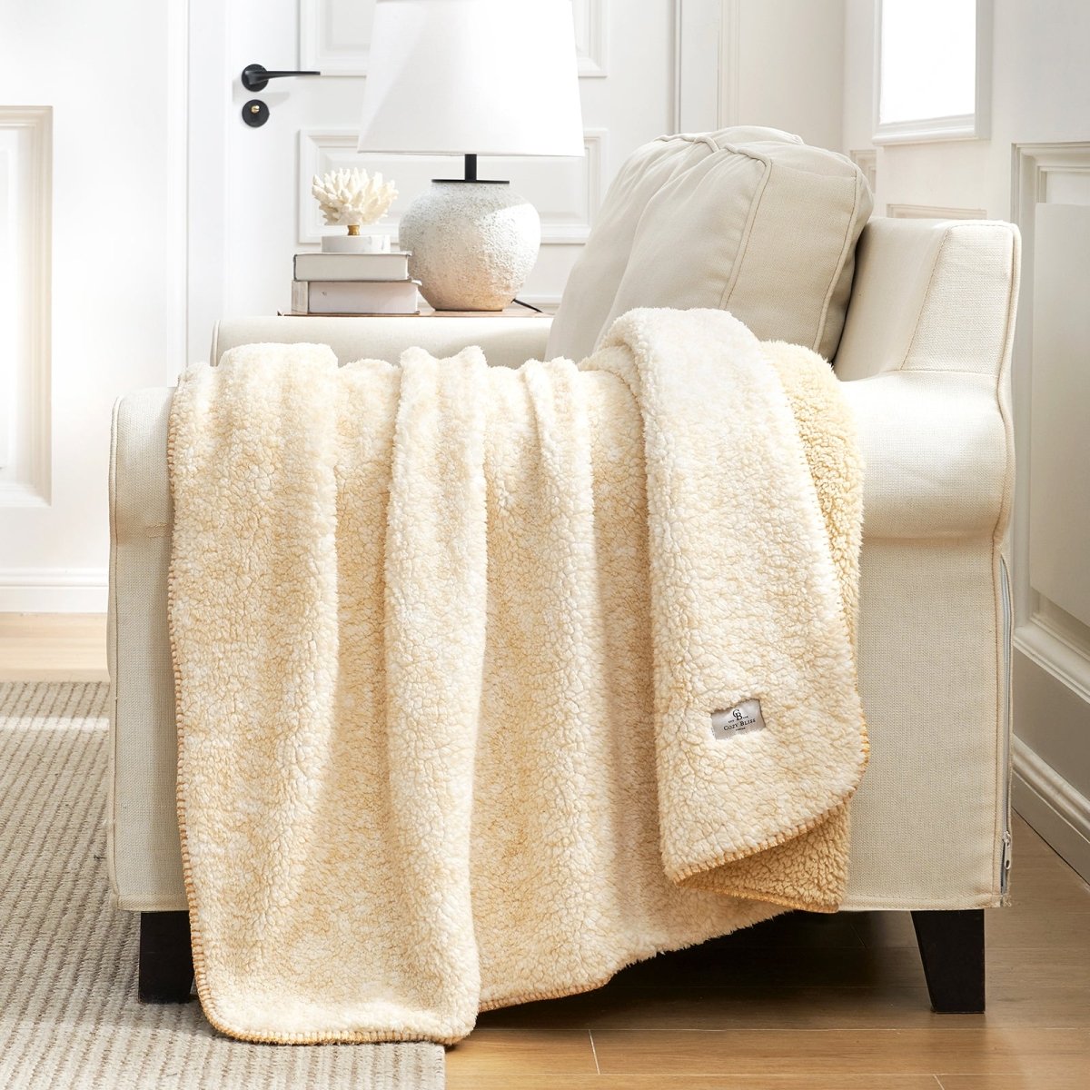 Cream Cozy Bliss Sherpa throw blanket on sofa. Soft, reversible and cozy blanket for home. #color_ Mottled Beige