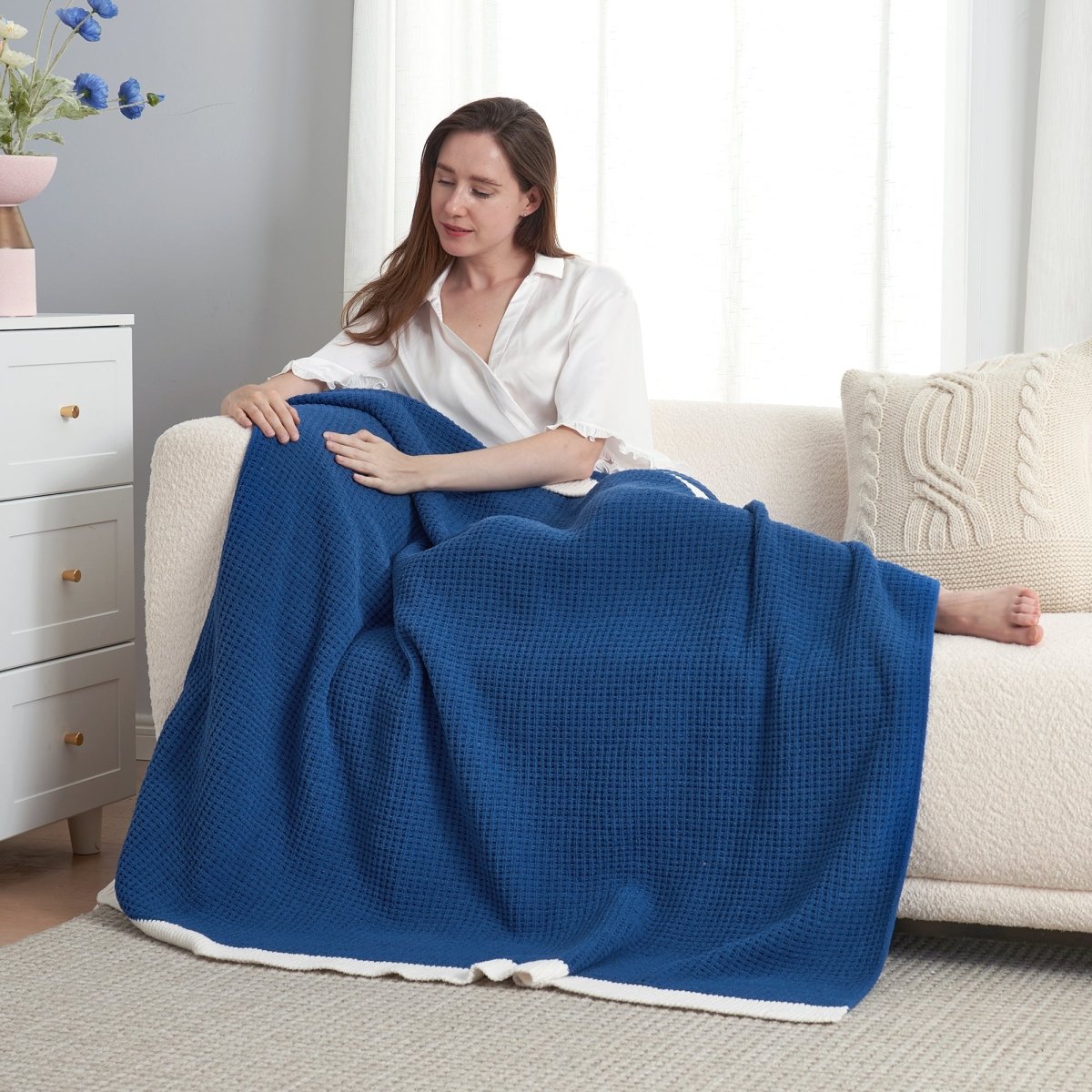 Woman resting on a sofa with a Chenille Waffle Knit Throw Blanket in Dark Blue. #color_Dark Blue