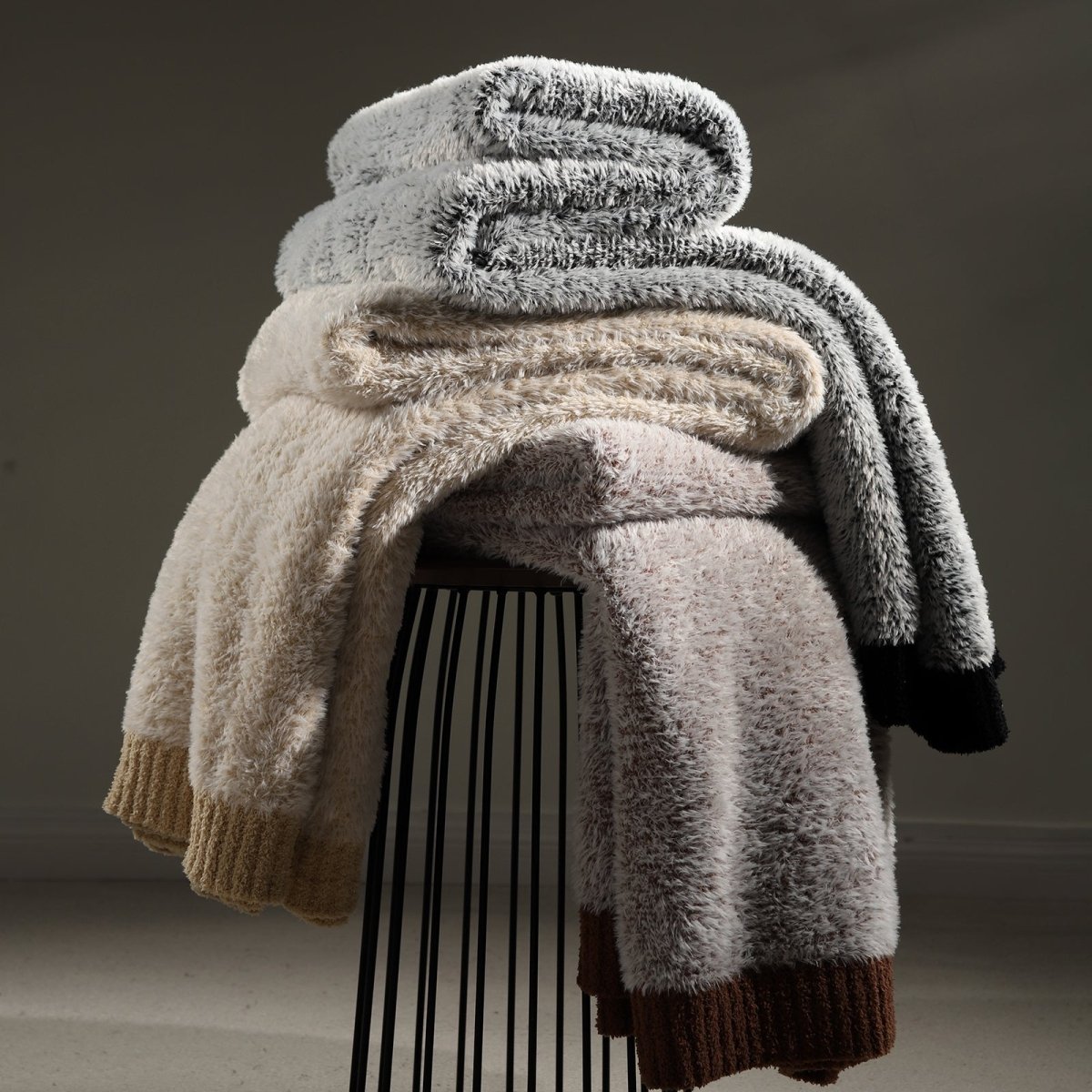 Faux Mink Feather Knit Throw Blanket stacked with different colors, showcasing multiple color options and soft texture.