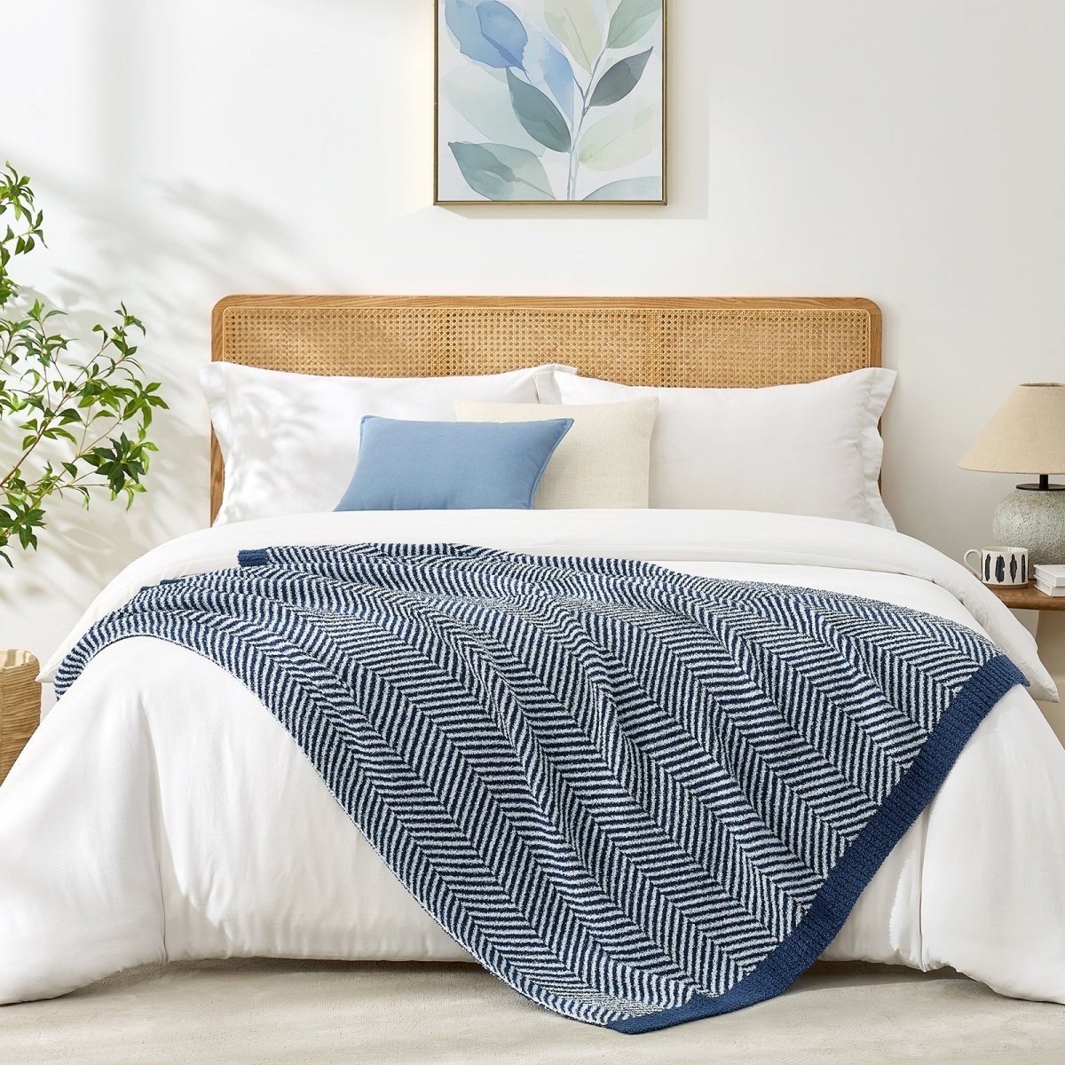 Reversible herringbone feather yarn knit throw blanket styled across a modern white bed #color_Navy Blue
