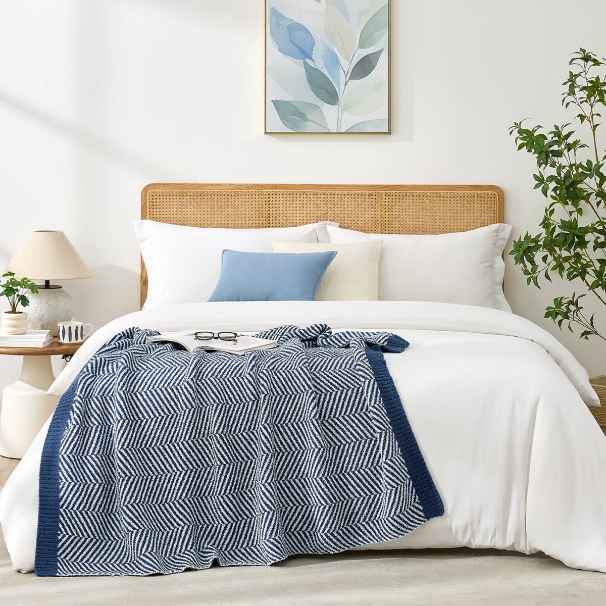 Reversible herringbone feather yarn knit throw blanket styled across a modern white bed #color_Navy Blue