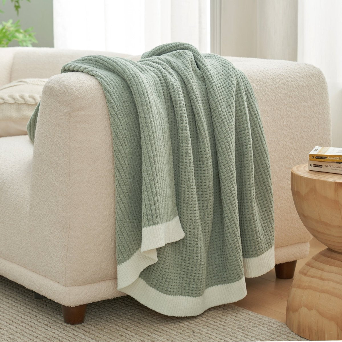 Chenille Waffle Knit Throw Blanket in Sage Green draped over a sofa, showcasing its soft tone and cozy texture. #color_Sage Green