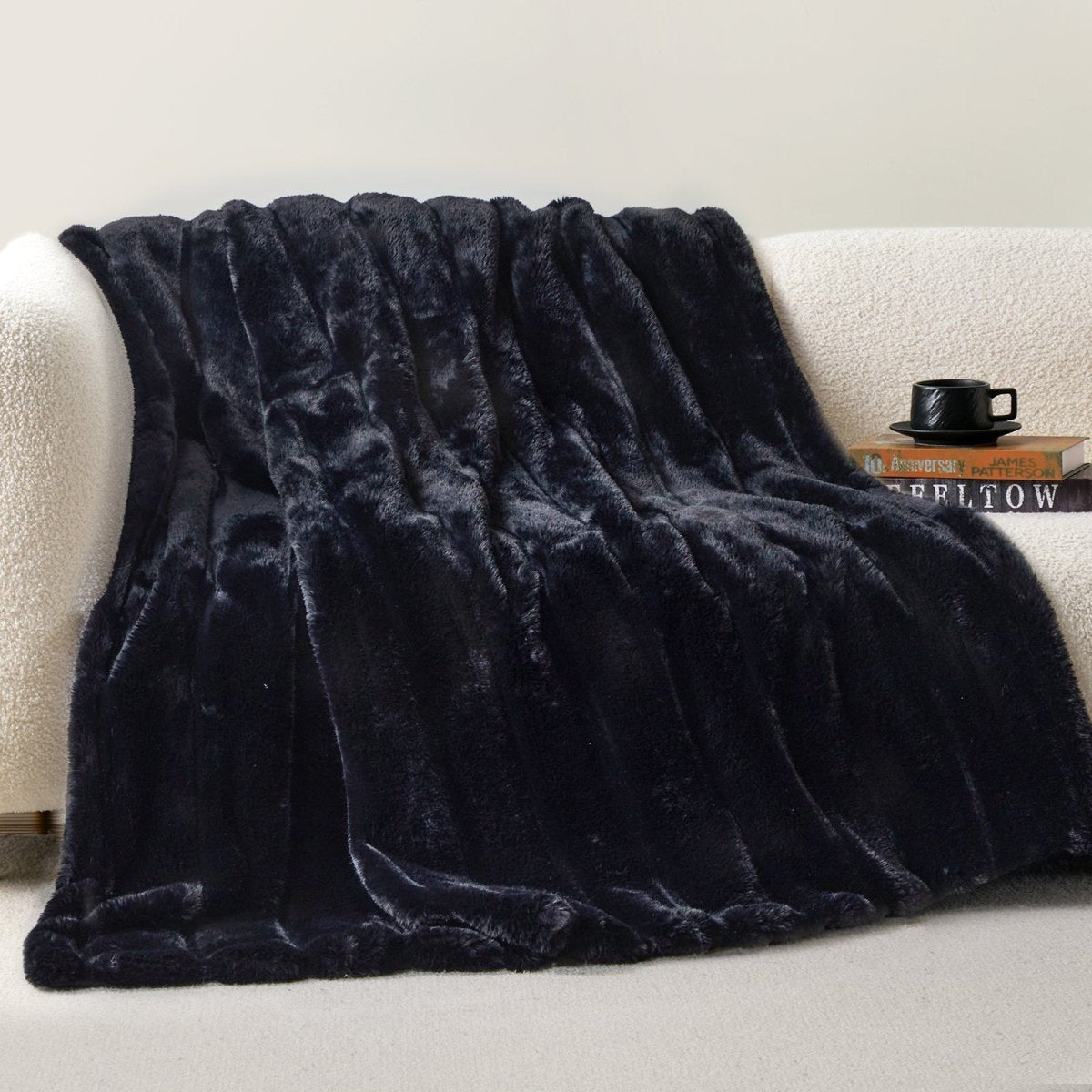 Cozy Bliss sheared faux fur throw blanket draped over a sofa, showcasing elegant ribbed texture #color_Black
