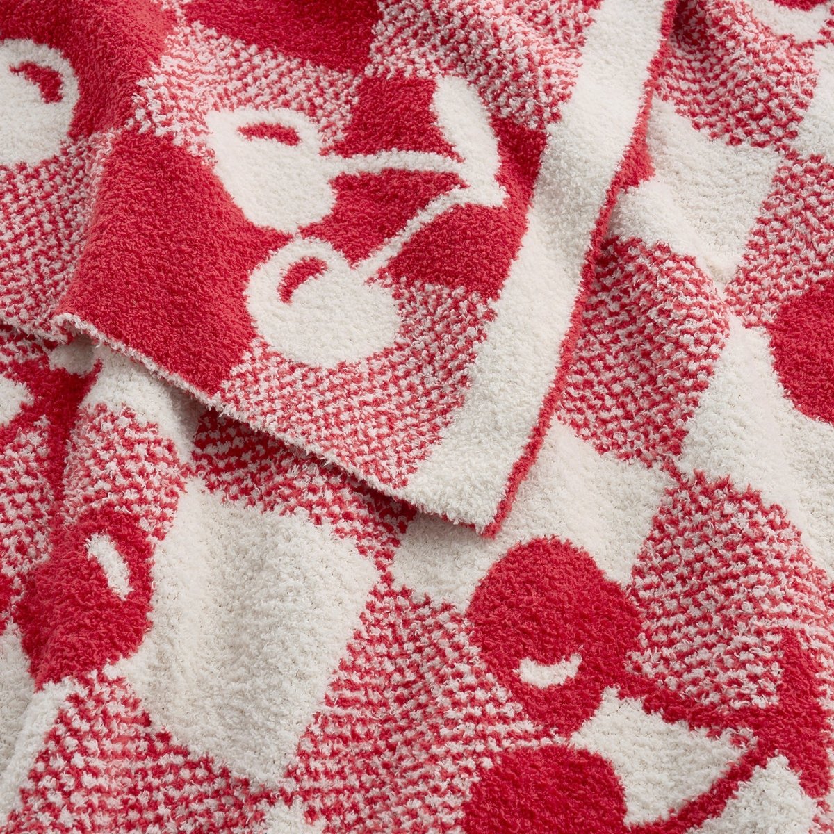 Close-up of cherry pattern on Reversible Checkered With Red Cherry Throw Blanket in Red Cherry highlighting soft feather yarn texture and plush feel. #color_Red Cherry