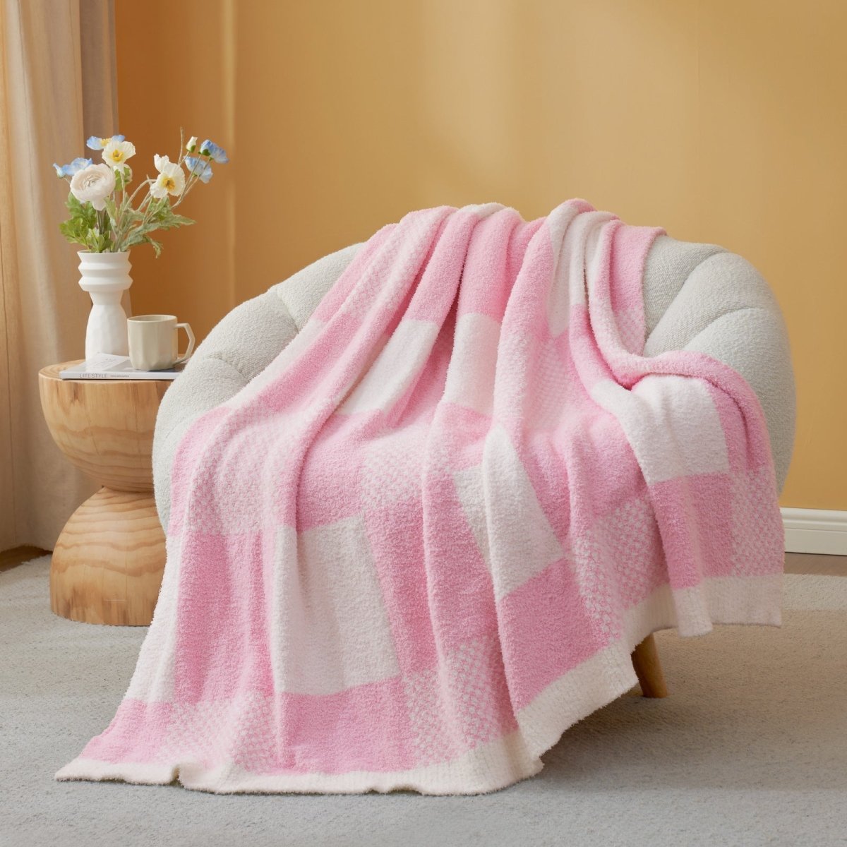 Pink and white checkered blanket draped over a chair in a cozy room.#color_Pink White