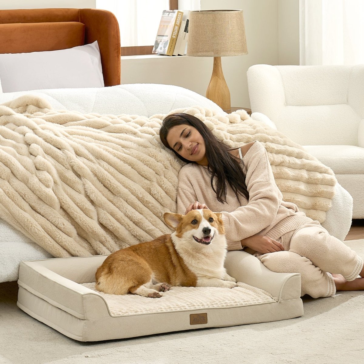 Dog lying on a Cozy Bliss Beige pet bed in a living room with a woman sitting beside it.#Color_Beige