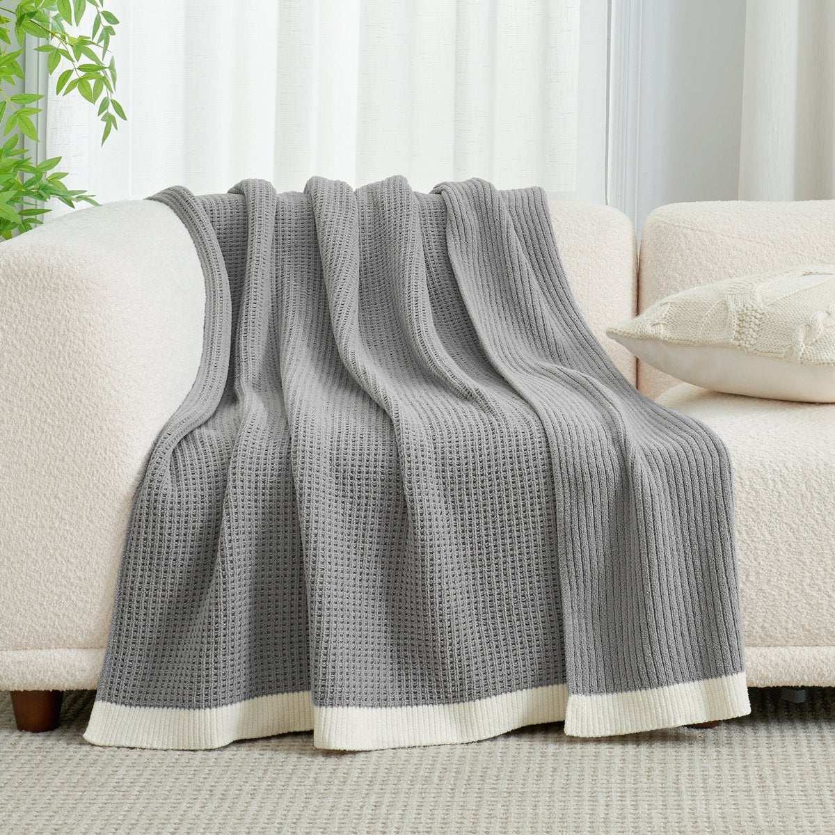 Chenille Waffle Knit Throw Blanket in Grey draped over a sofa, showcasing its soft waffle knit texture and cozy design. #color_Grey