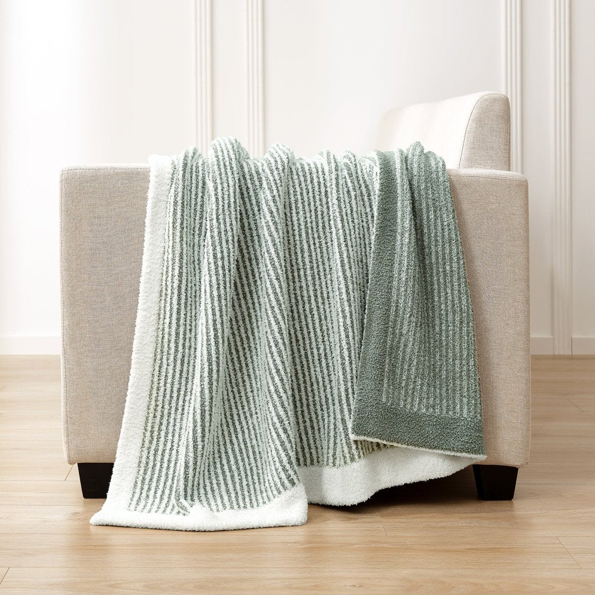 Soft Ribbed Feather Yarn Throw Blanket in Sage Green draped over the back of a sofa, highlighting soft ribbed texture and cozy fabric feel. #color_Sage Green
