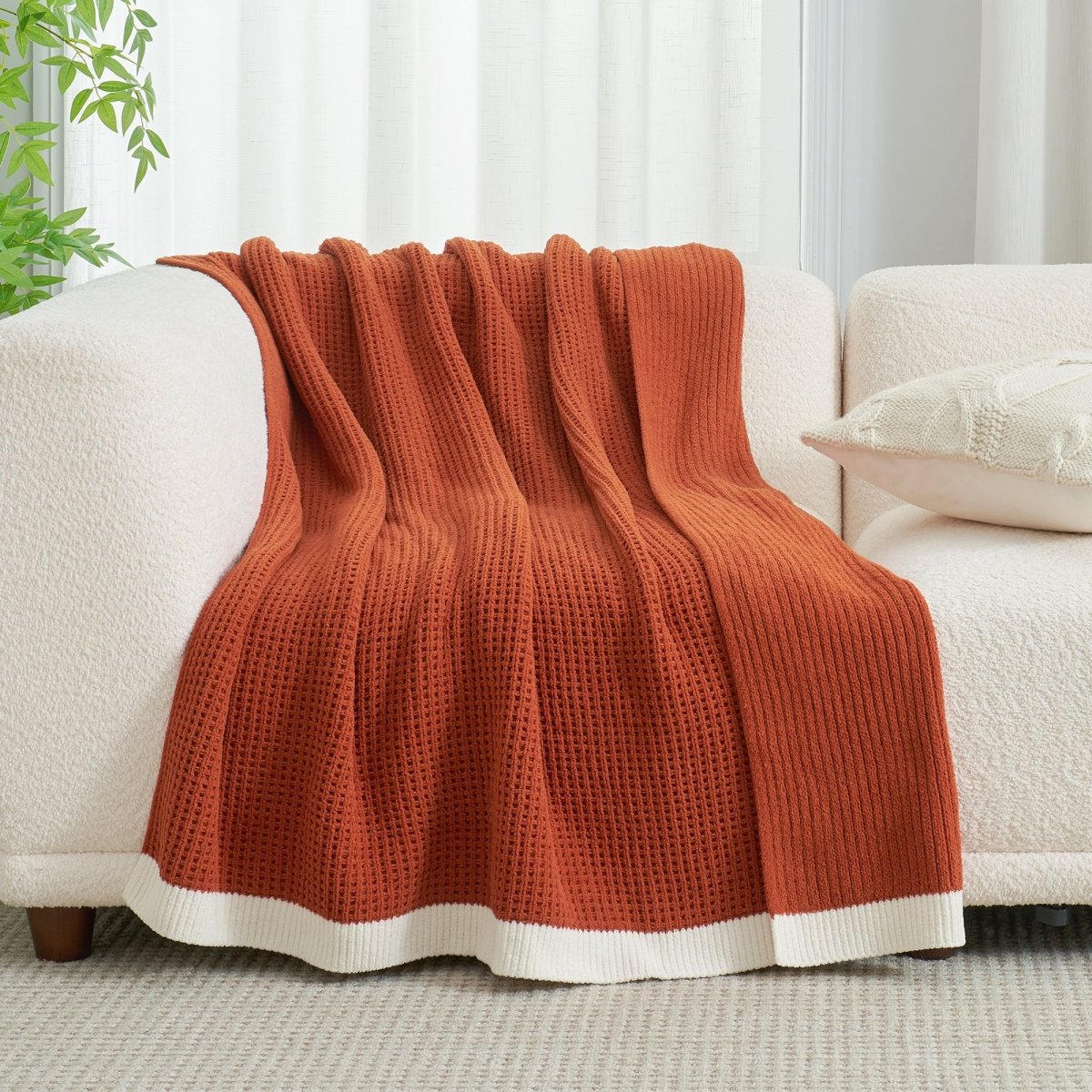 Chenille Waffle Knit Throw Blanket in Burnt Orange draped over a sofa, showcasing its rich warm tone and soft texture. #color_Burnt Orange