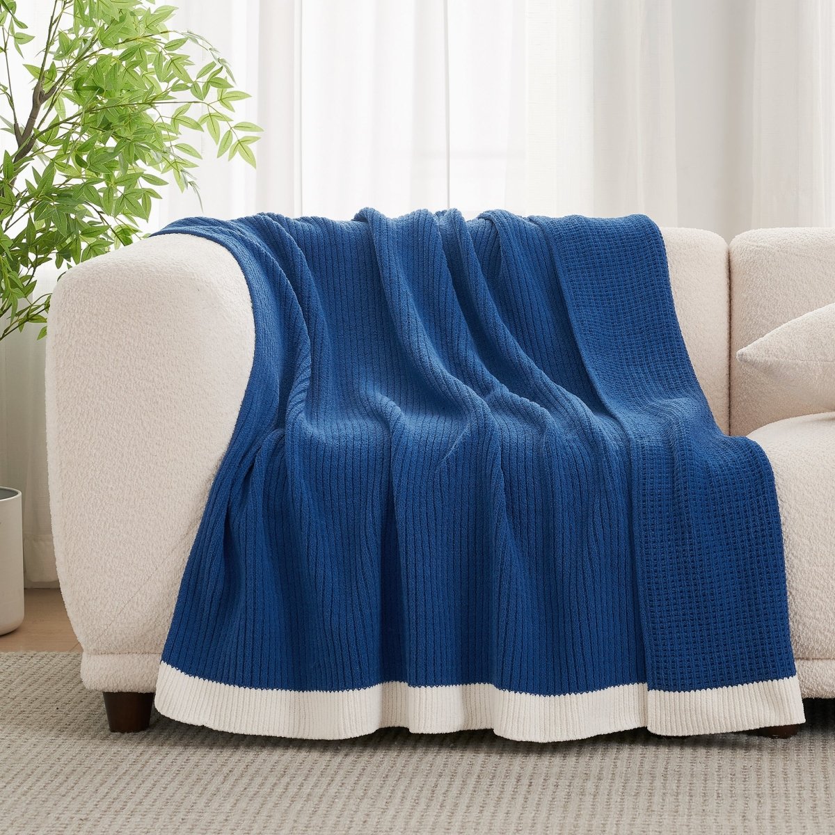 Chenille Waffle Knit Throw Blanket in Dark Blue draped over a sofa, showcasing its deep tone and soft texture. #color_Dark Blue