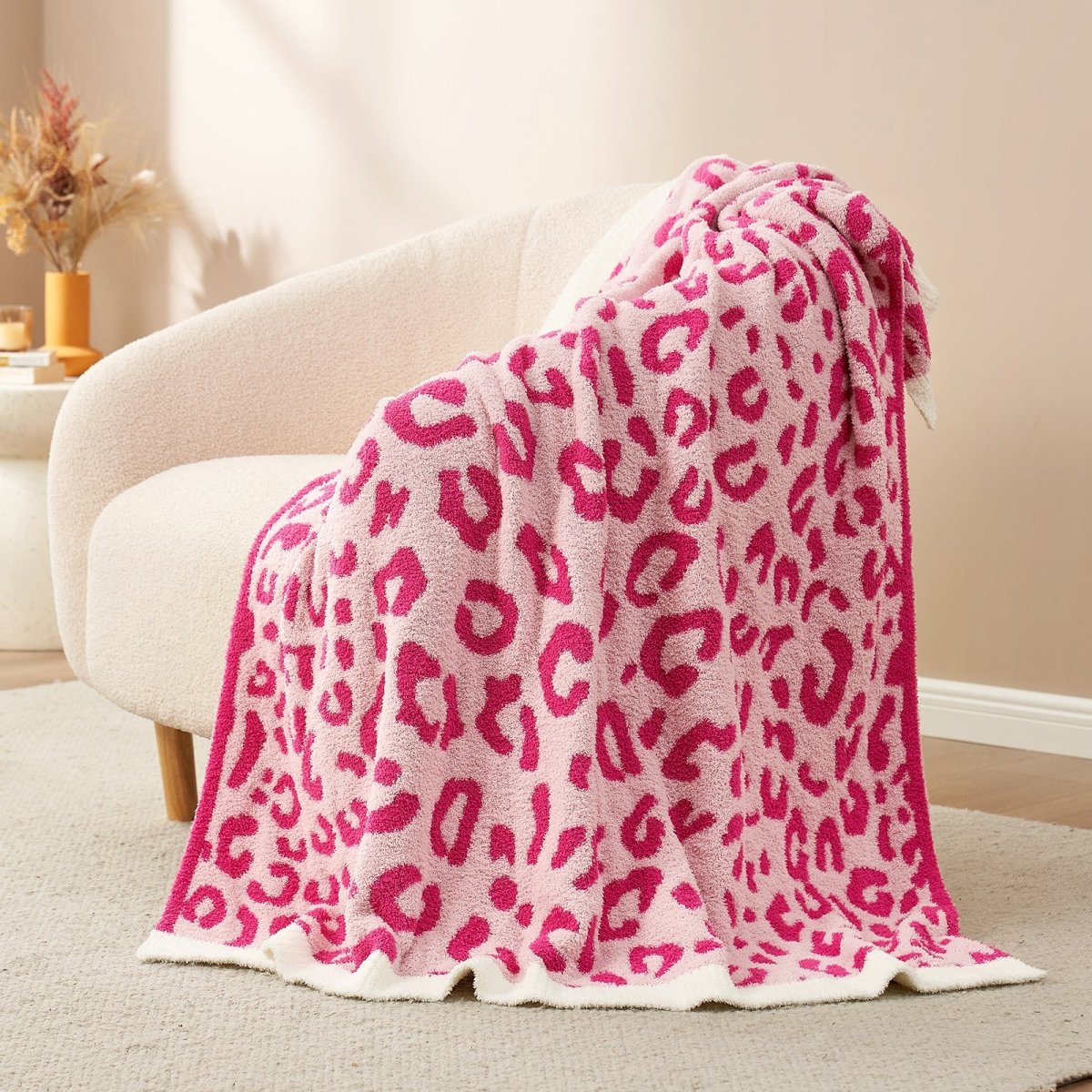 Reversible Leopard Feather Yarn Throw Blanket in Hot Pink draped over an armchair, showcasing its vibrant leopard pattern and soft texture. #color_Hot Pink