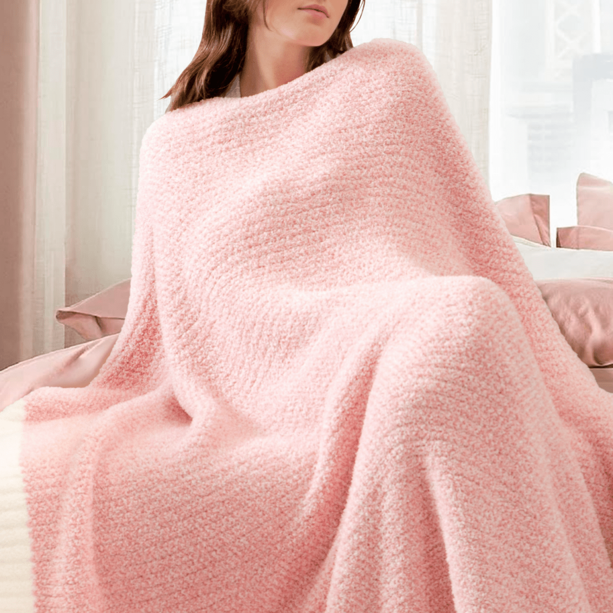 Woman wrapped in a Heather Feather Yarn Throw Blanket in Pink, enjoying relaxation. #color_Pink