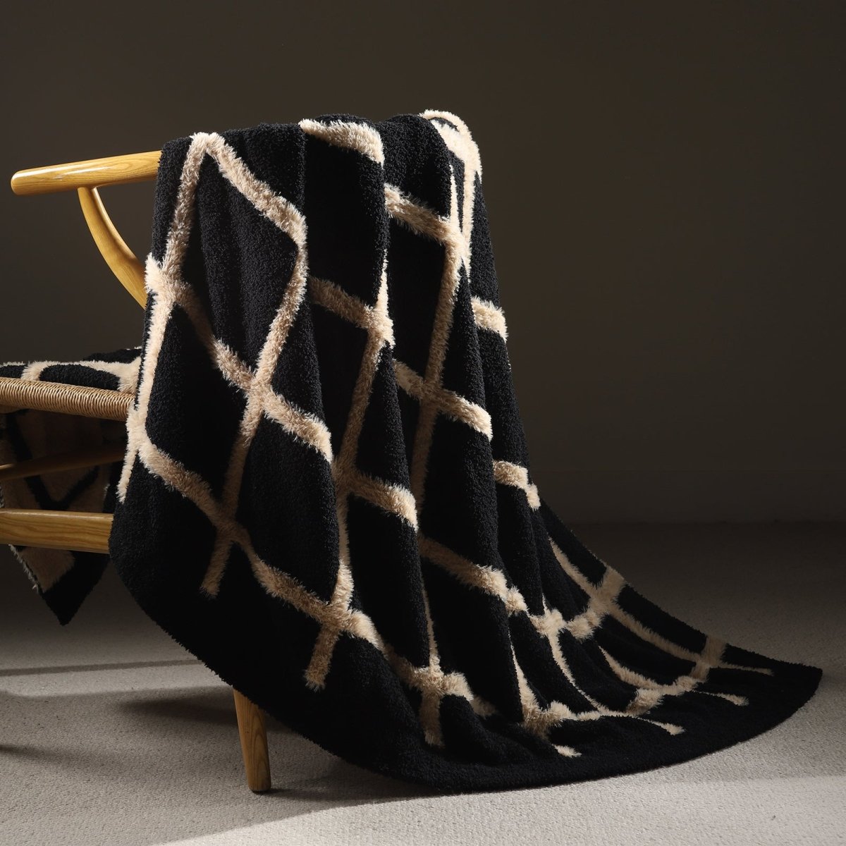 Faux Mink Textured Plaid Knit Throw Blanket in Black draped over a chair. #color_Black