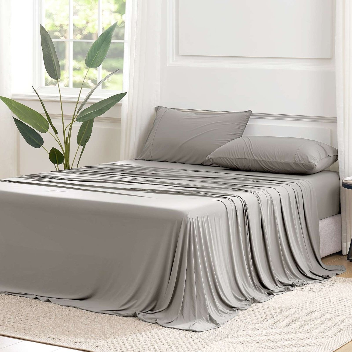 Cozy Bliss Outlast® Performance Cooling Sheet Set draped across a bed in a bright bedroom, showcasing the complete bedding appearance. #color_Grey