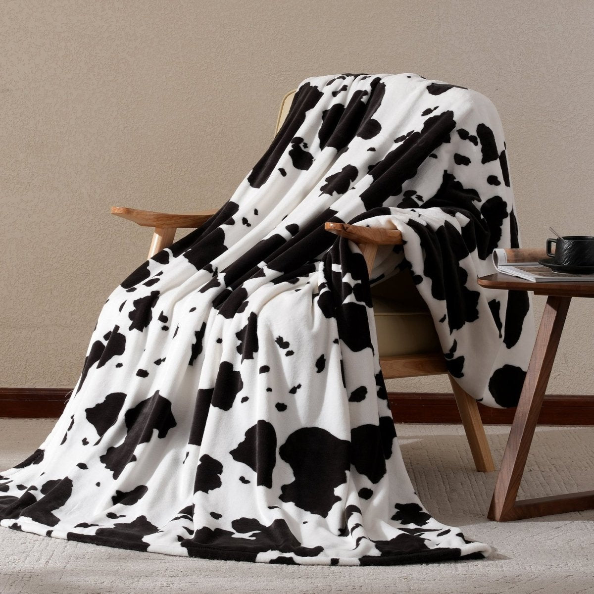 Cow print milkyplush throw blanket in Black & White draped over a chair, creating a cozy and stylish corner #color_Black & White