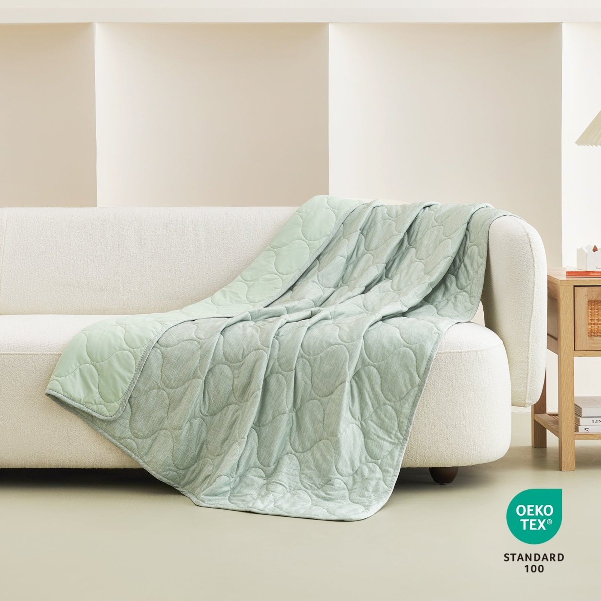 Cozy Bliss sage green cooling blanket draped over a sofa #color_Sage Green