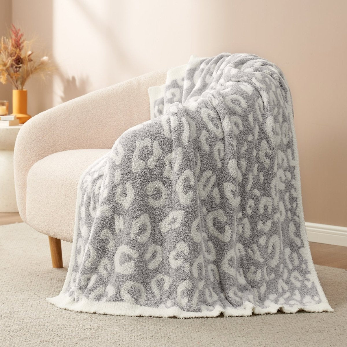 Reversible Leopard Feather Yarn Throw Blanket in Leopard Grey draped over an armchair, showcasing its soft texture and modern leopard pattern. #color_Leopard Grey