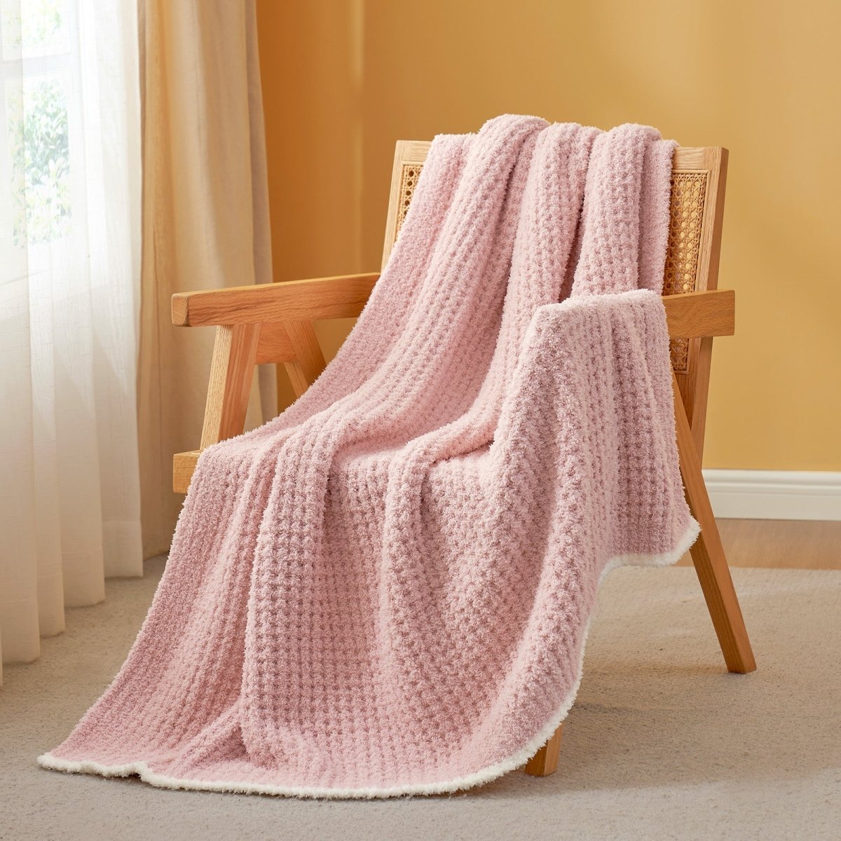Soft Waffle Feather Yarn Throw Blanket in Pink draped over an armchair, creating a warm atmosphere. #color_Pink