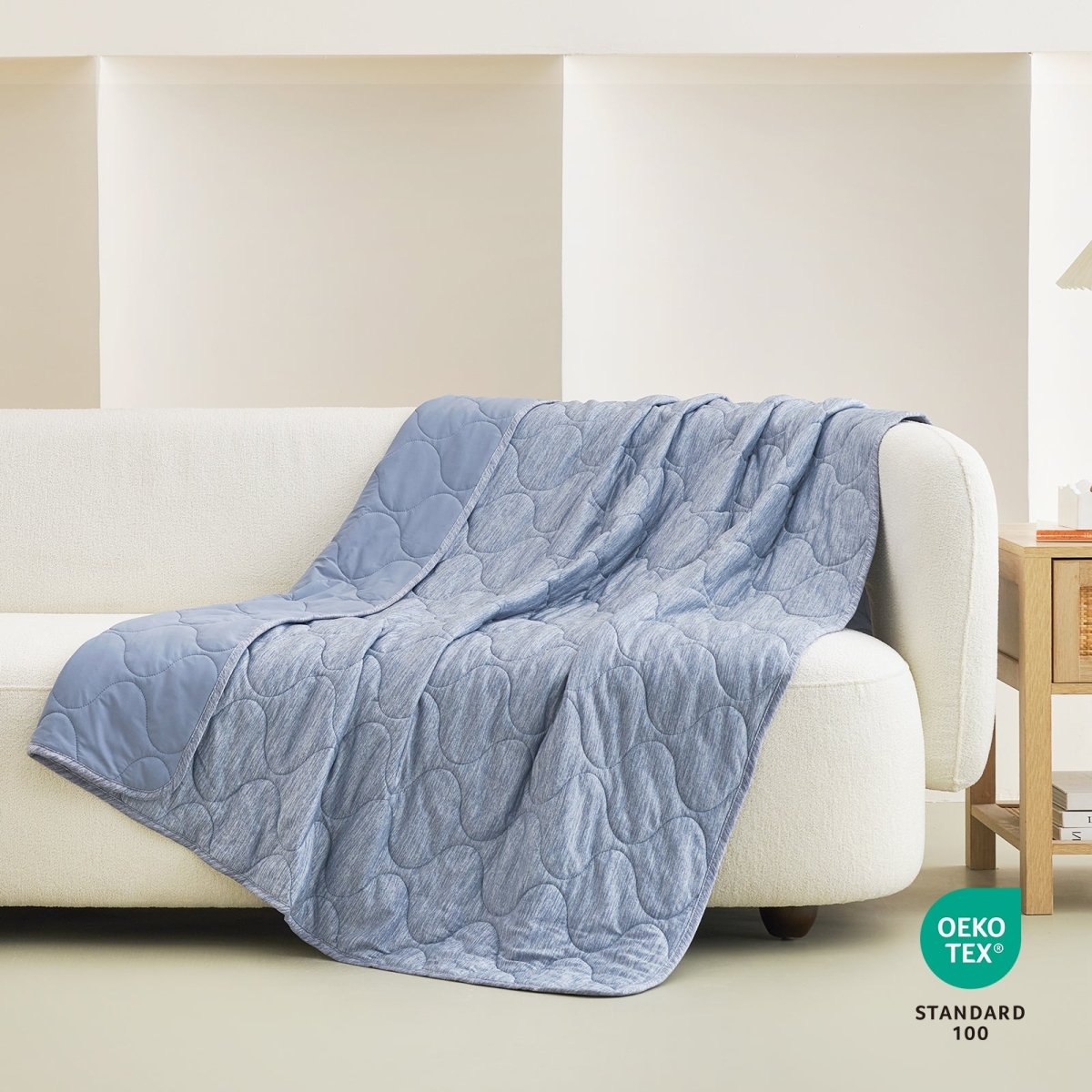 Cozy Bliss blue cooling blanket with cloud pattern on a white sofa, OEKO-TEX certified for cozy sleep. #color_Dark Blue