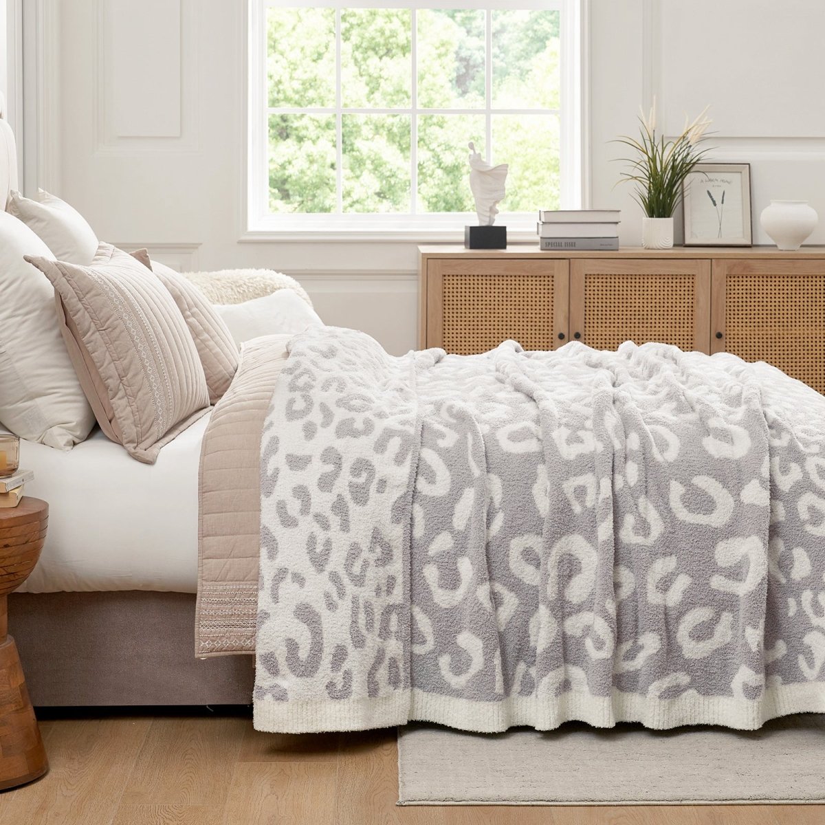 Reversible Leopard Feather Yarn Throw Blanket in Leopard Grey styled on a bed, adding a calm and cozy layered look. #color_Leopard Grey