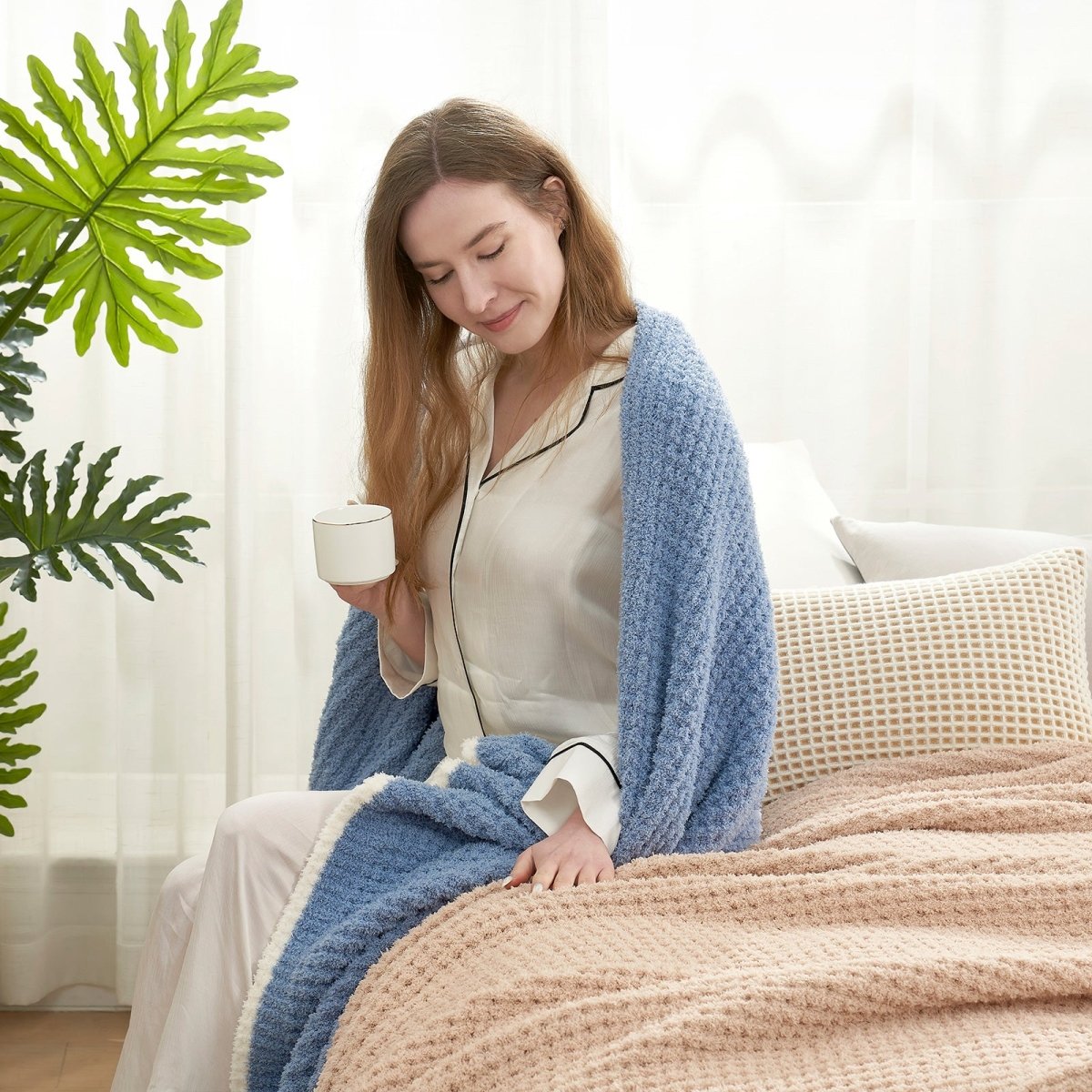Woman enjoying a cup of coffee with a Soft Waffle Feather Yarn Throw Blanket in Dark Blue in a bright room setting. #color_Dark Blue