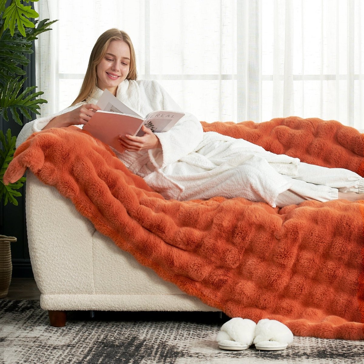 Women reading a magazine while lying on Cozy Bliss burnt orange faux fur throw blanket #color_Burnt Orange