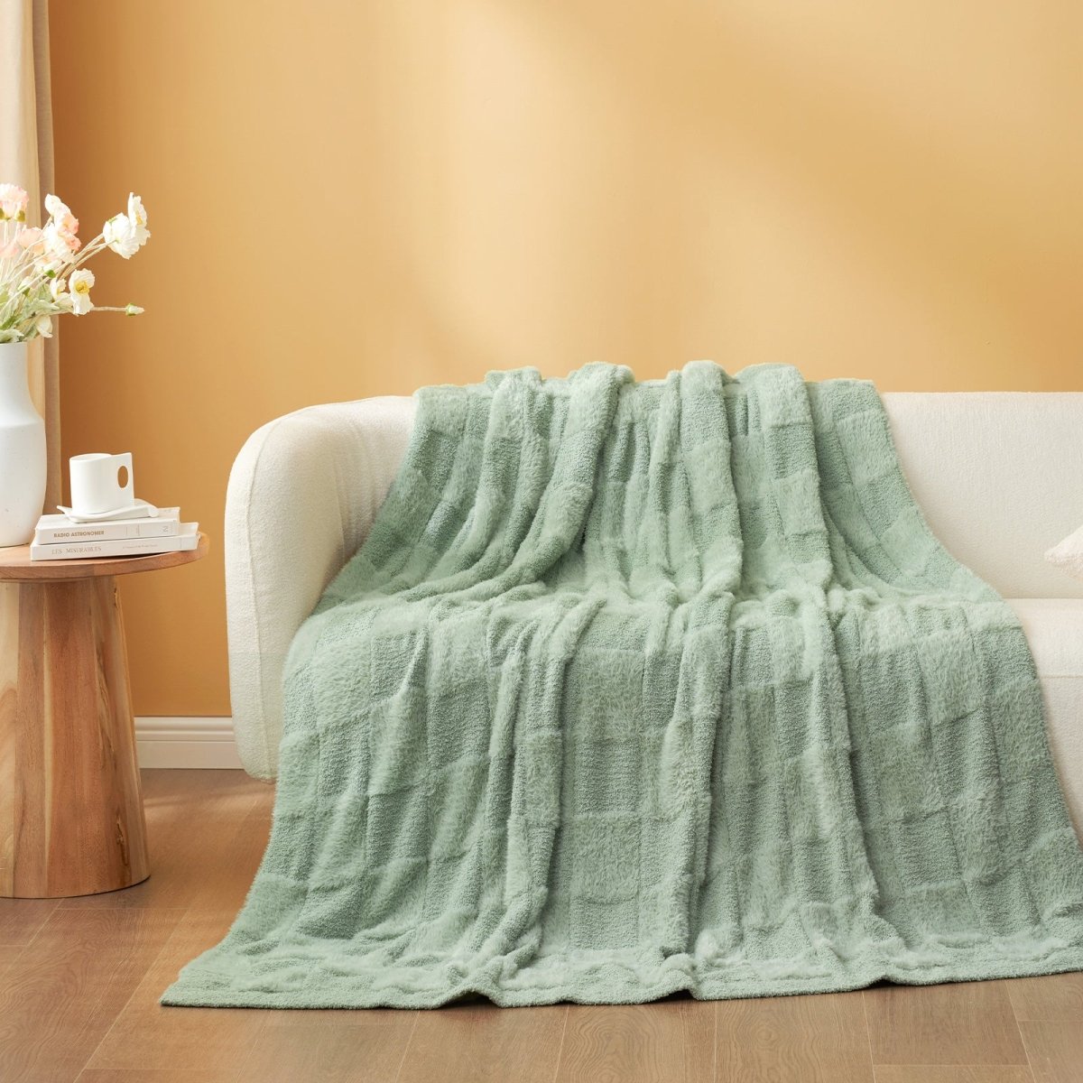 Checkered Faux Fur Feather Yarn Throw Blanket in Sage Green draped over a sofa, highlighting its fresh tone. #color_Sage Green