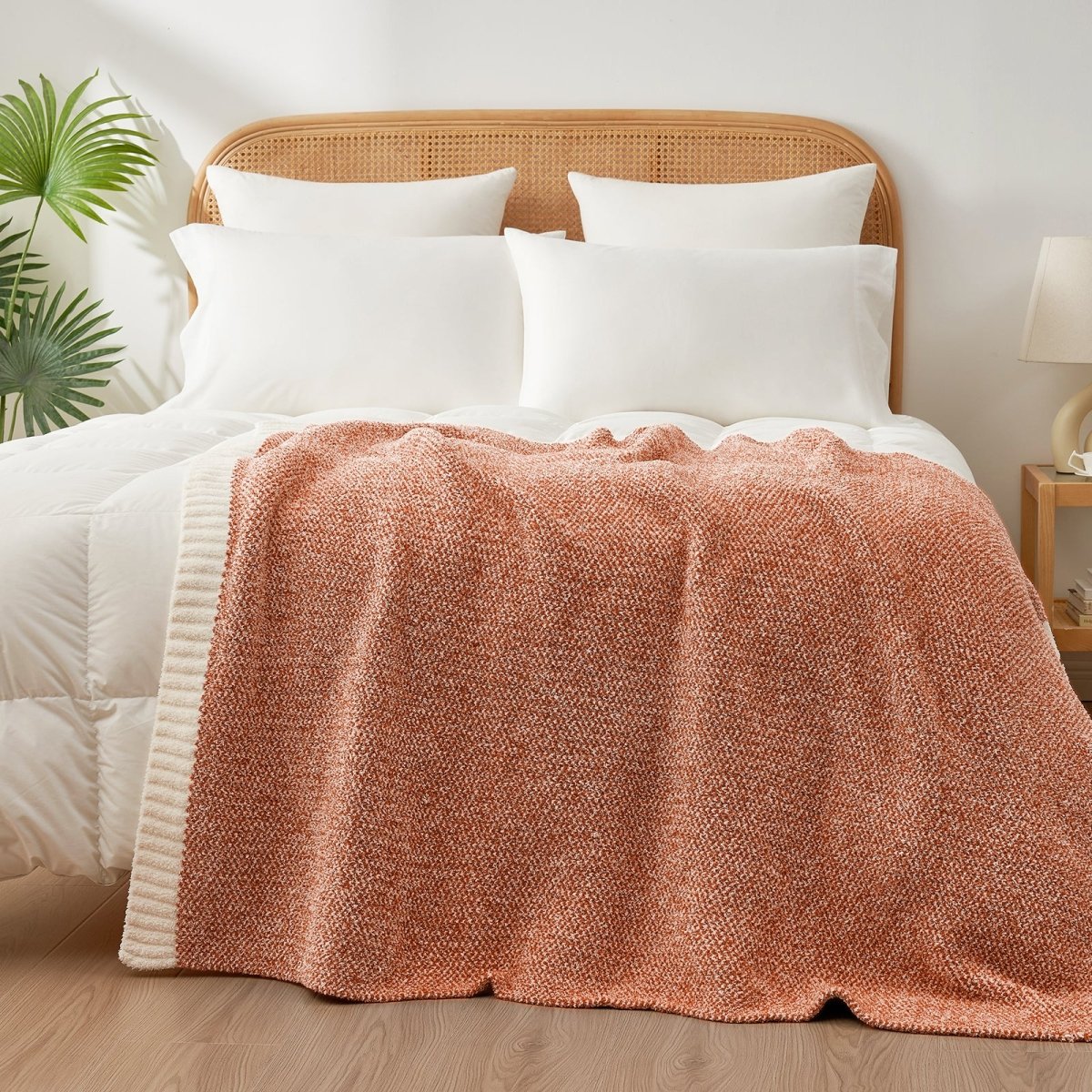 Heather Feather Yarn Throw Blanket in orange styled on a bed, enhancing bedroom decor with a soft, elegant and cozy layered look.  #Color_Orange