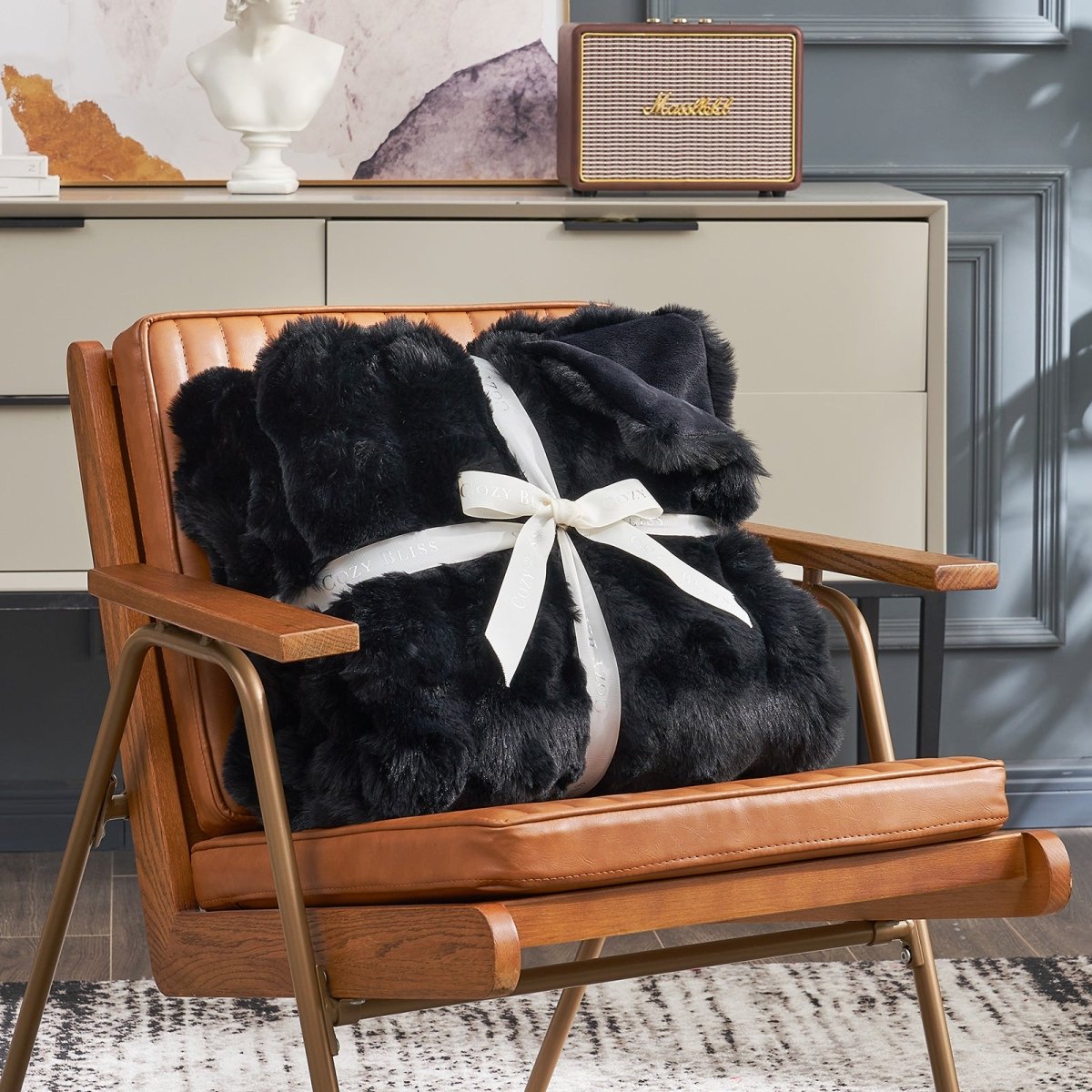 Fluffy black blanket with a bow on an armchair. #color_Black