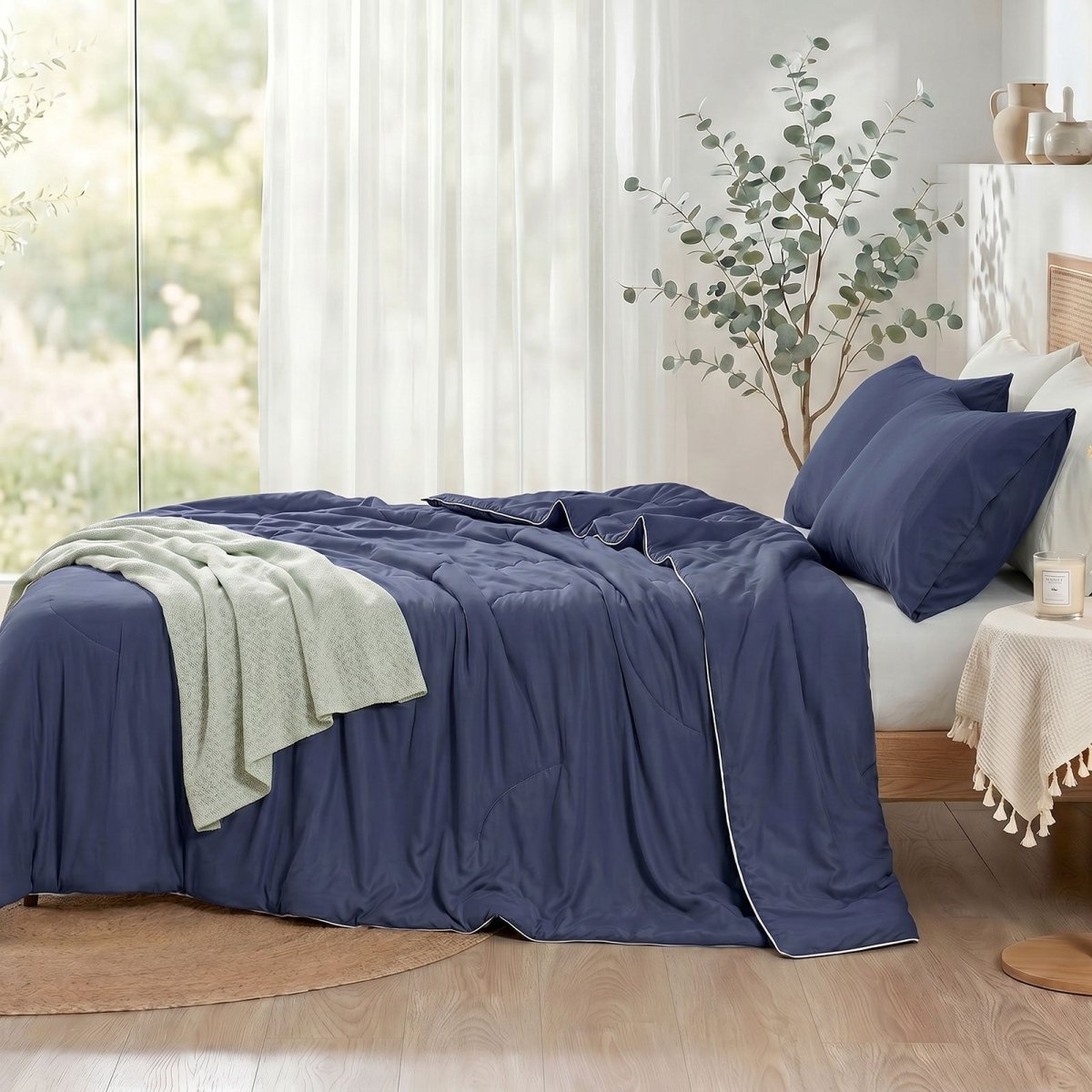 Cozy Bliss double-sided cooling comforter on a bed in a bright, sunlit bedroom with green plants, lightweight summer bedding for hot sleepers.#color_Navy Blue