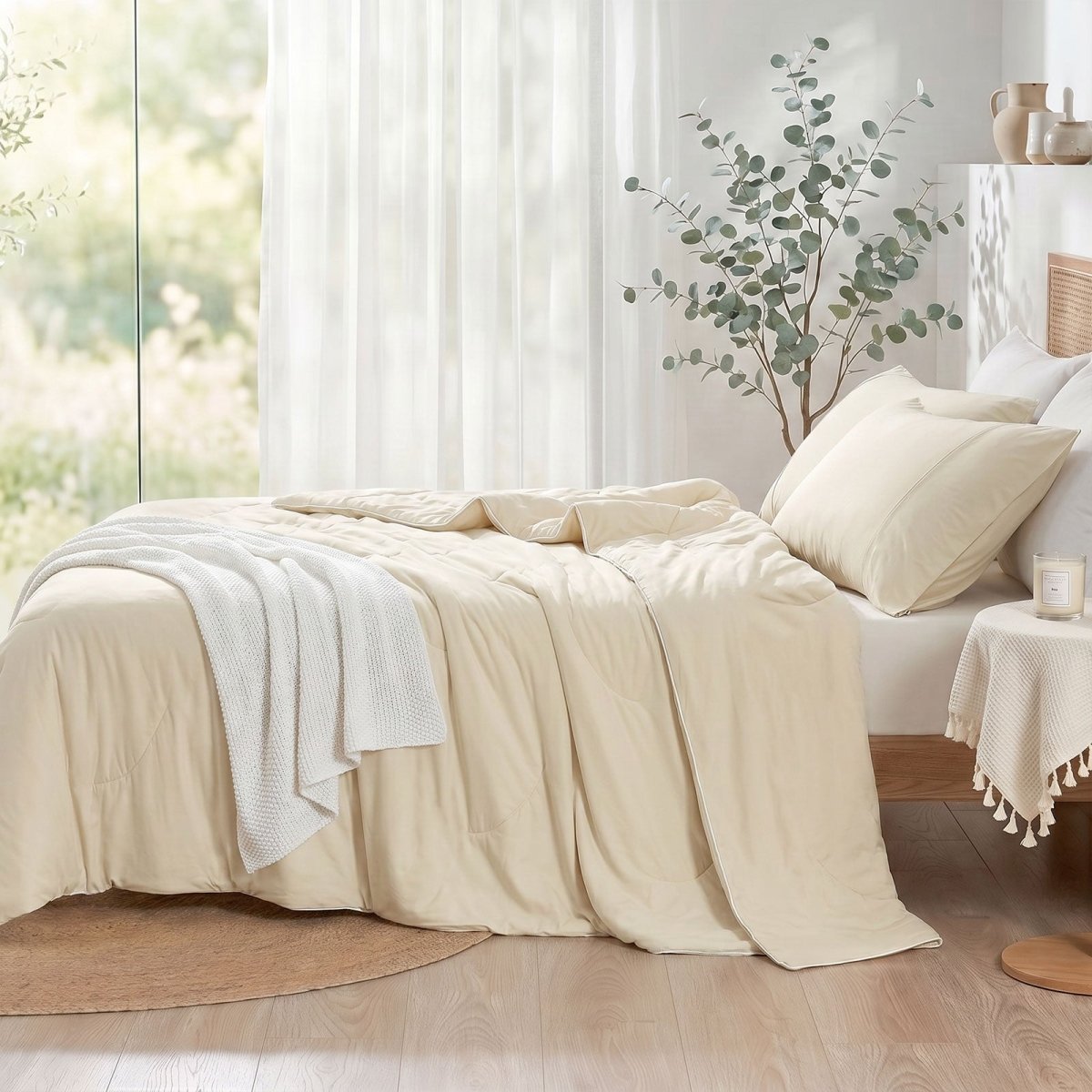 Cozy Bliss double-sided cooling comforter on a bed in a bright, sunlit bedroom with green plants, lightweight summer bedding for hot sleepers.#color_Beige