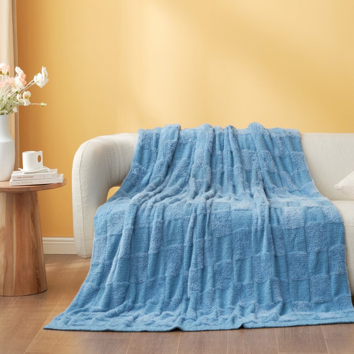 Checkered Faux Fur Feather Yarn Throw Blanket in Blue draped over a sofa, highlighting its modern style. #color_Misty Blue