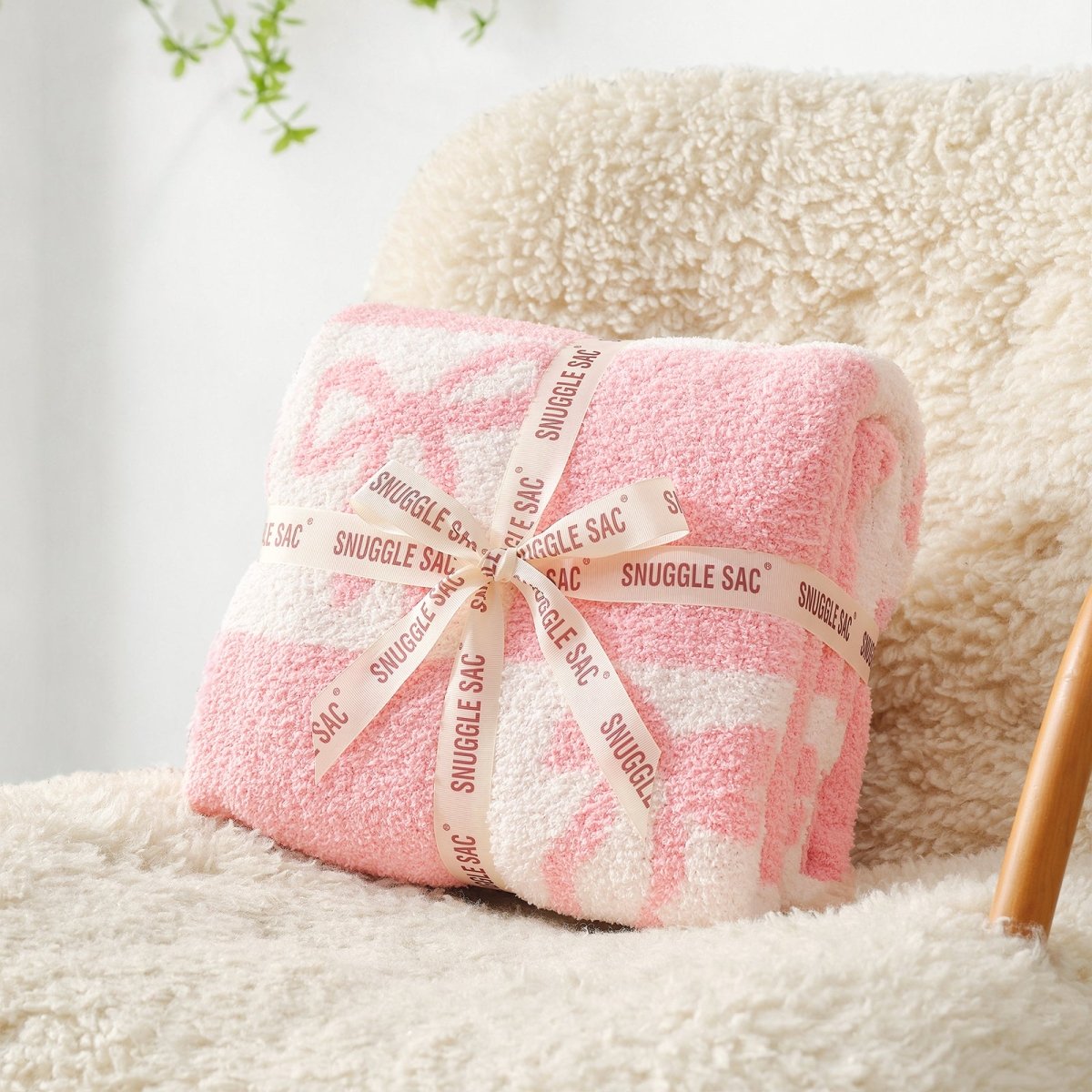 Reversible Checkered Bow Feather Yarn Throw Blanket in Pink neatly folded with ribbon packaging on a cozy chair, perfect as a soft gift blanket. #color_Pink