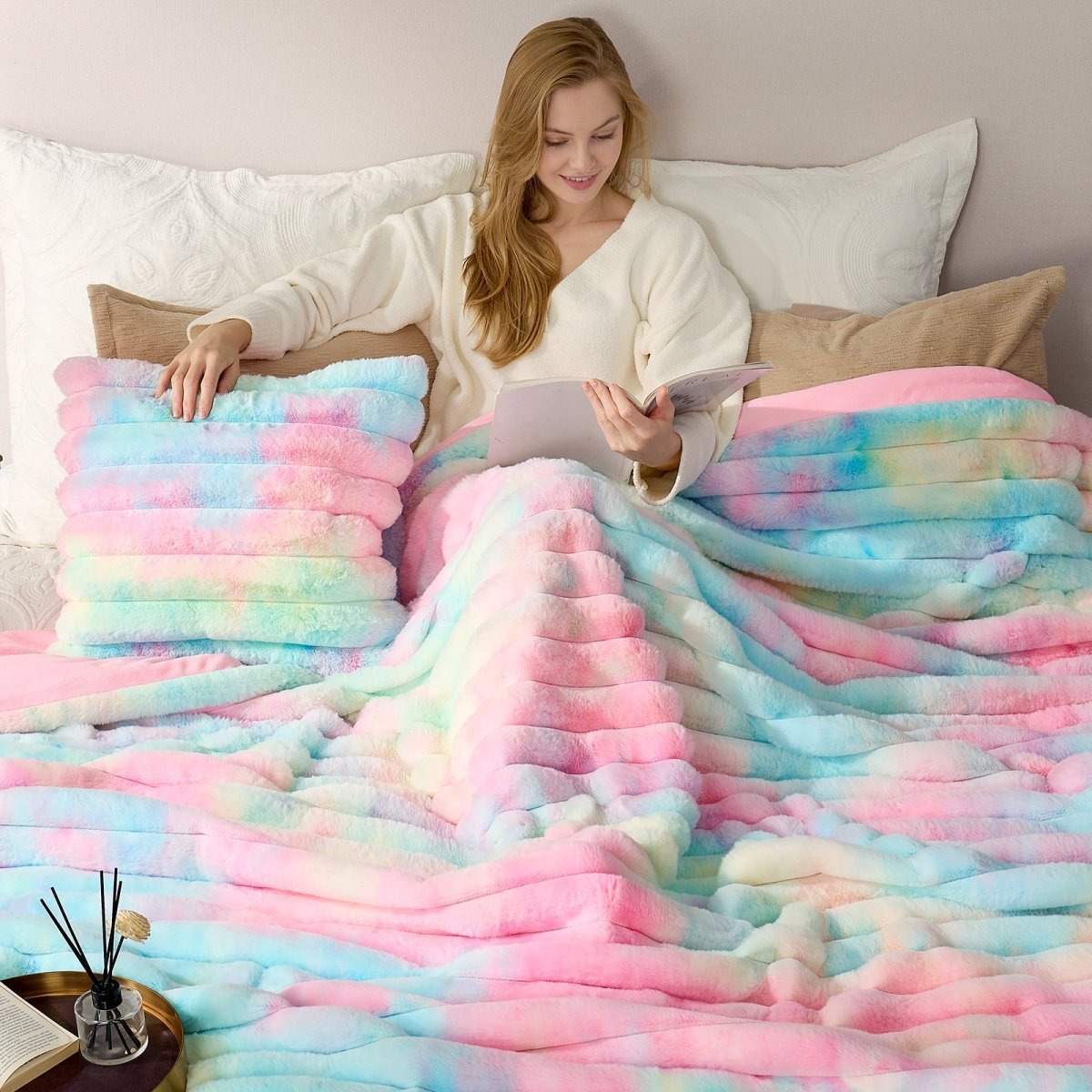 Woman reading a book under a colorful blanket on a bed. #color_Tie-dye Rainbow