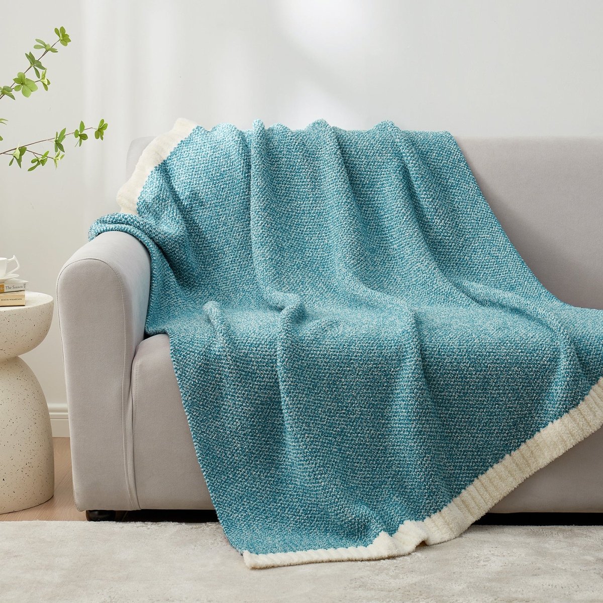 Heather Feather Yarn Throw Blanket in Heather Teal draped over a sofa, adding a refreshing and cozy touch. #color_Heather Teal