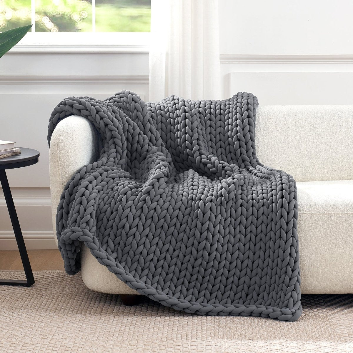 Cozy Bliss Performance Cooling Weighted Blanket chunky knit blanket draped on sofa#color_Charcoal Grey