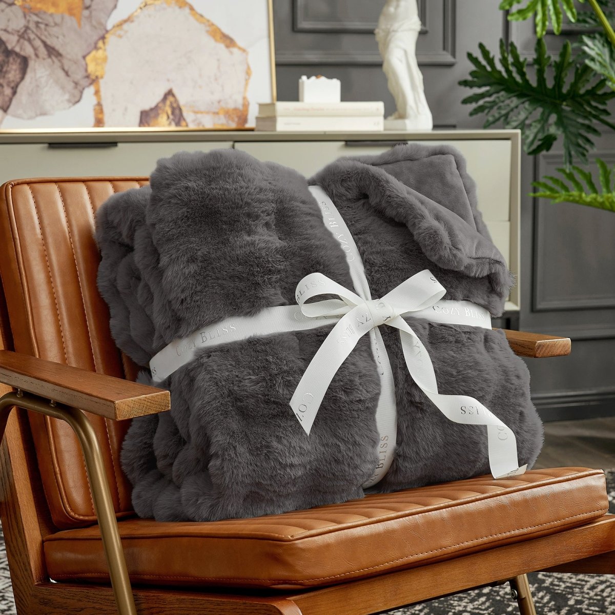 Fluffy charcoal grey blanket with a bow on an armchair. #Color_ Charcoal Grey