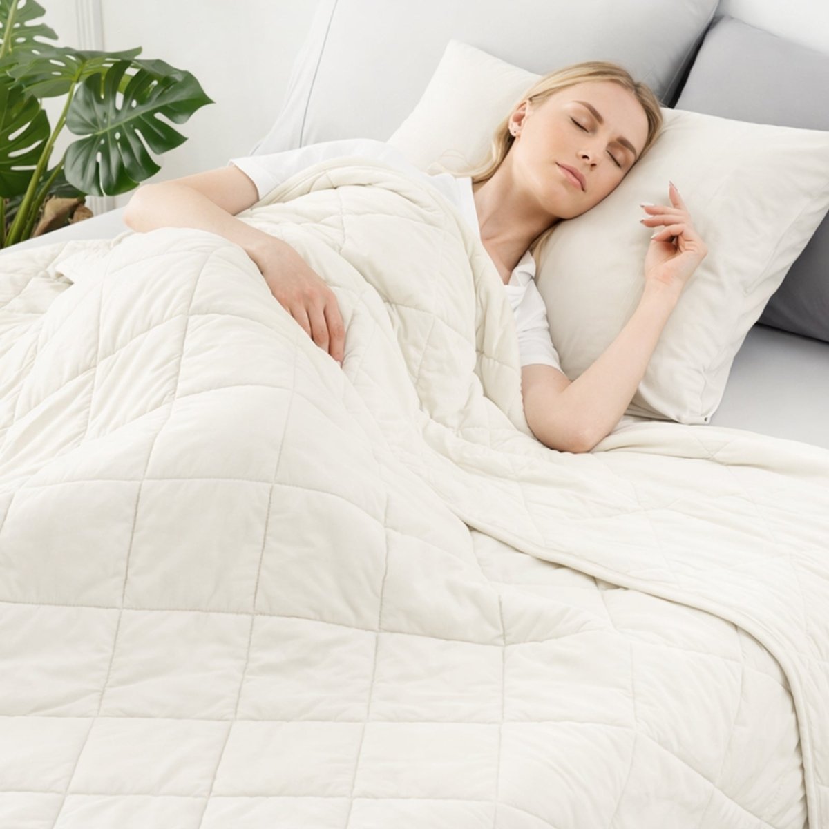 Woman sleeping under a white comforter in a cozy bedroom setting.   #color_Off White