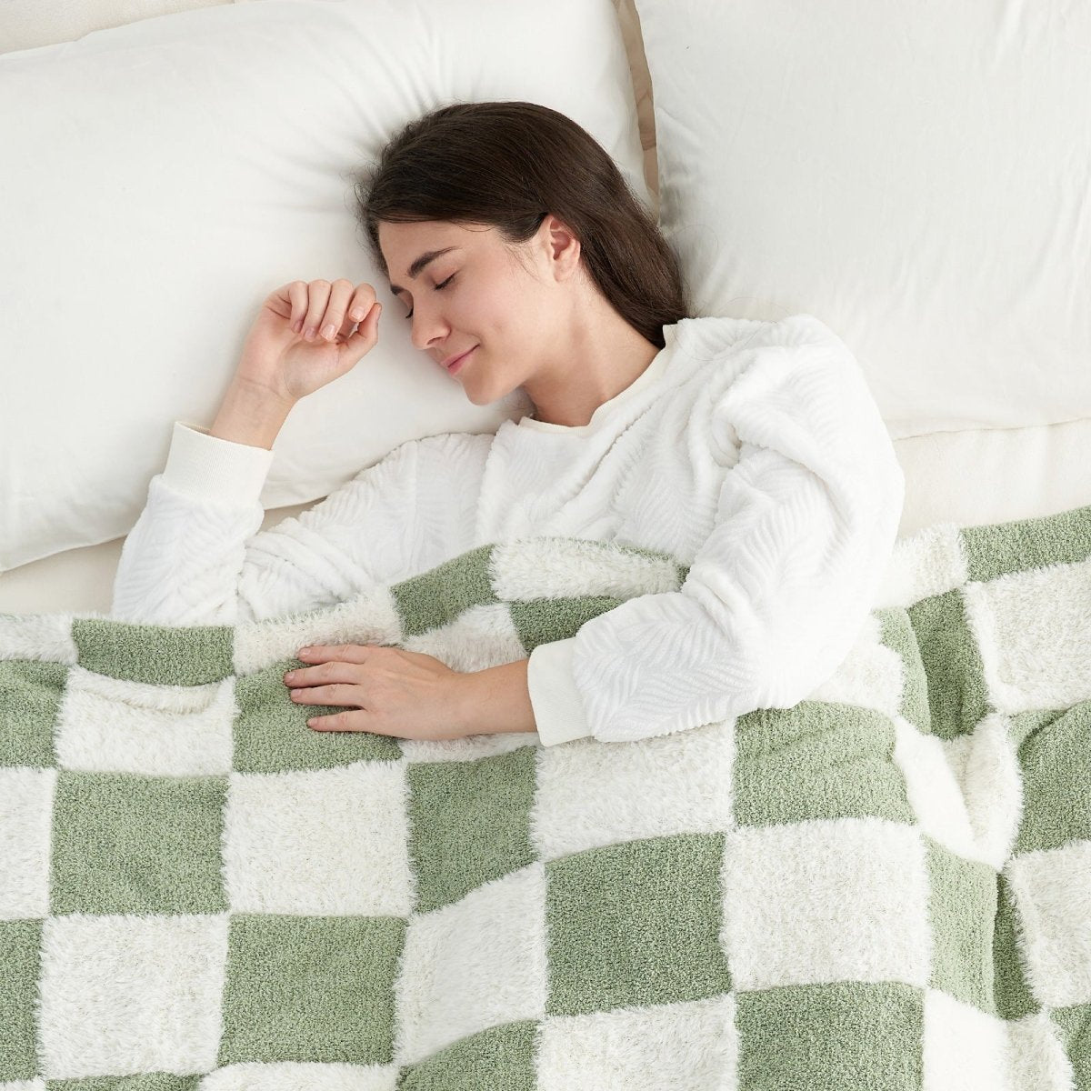 Woman sleeping under a Checkered Faux Fur Feather Yarn Throw Blanket in Sage Green & White, offering comfort and warmth. #color_Sage Green & White