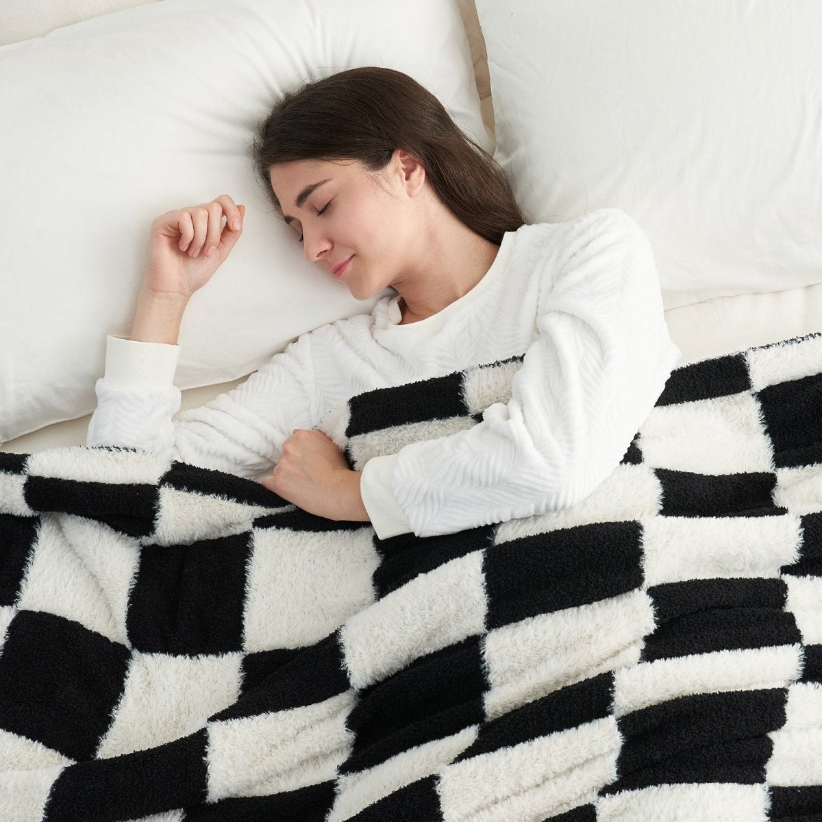 Woman sleeping under a Checkered Faux Fur Feather Yarn Throw Blanket in Black & White, providing cozy warmth. #color_Black & White