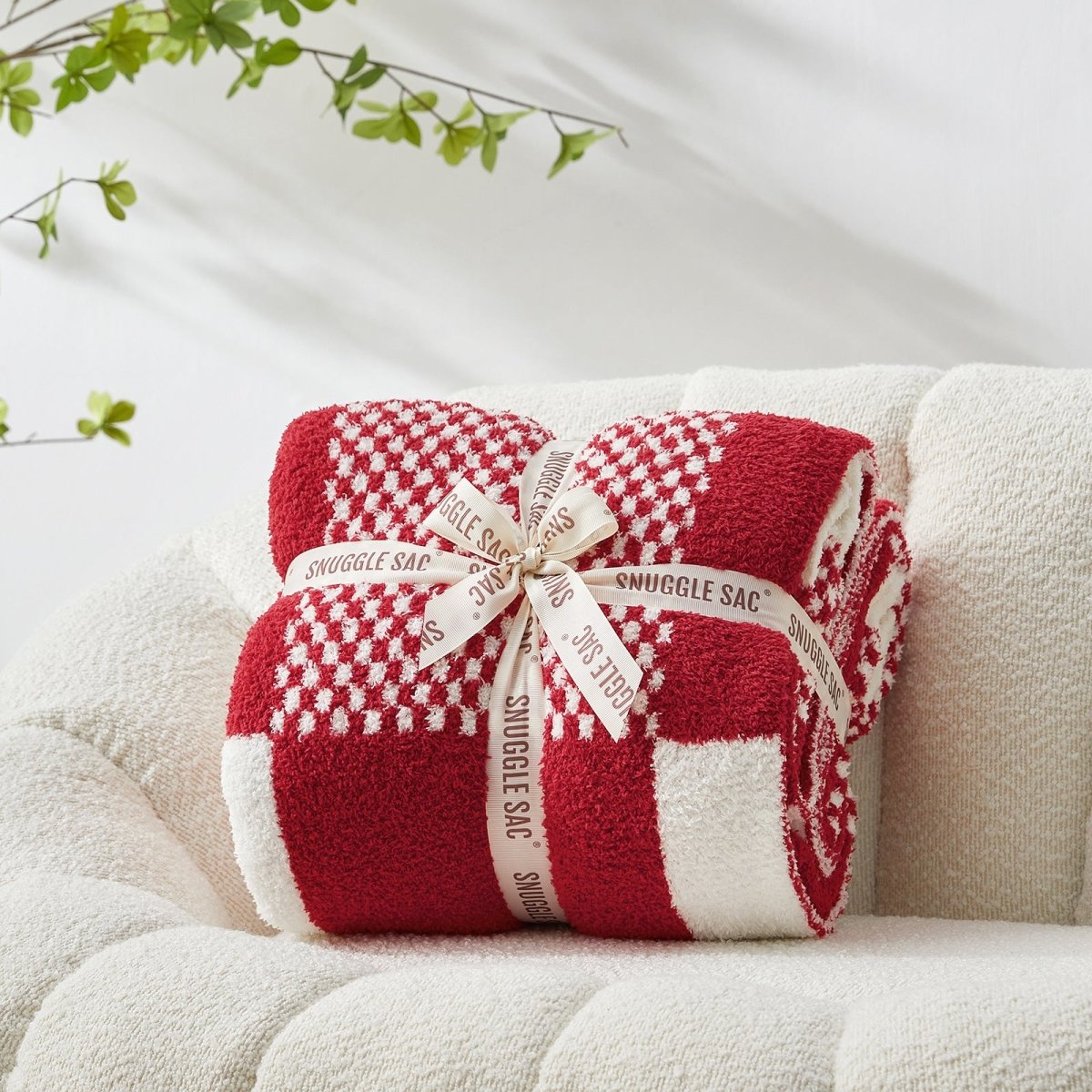 Checkered Feather Yarn Throw Blanket in Red & Cream front view neatly folded on a sofa, showcasing soft texture and checkered pattern design. #color_Red & Cream