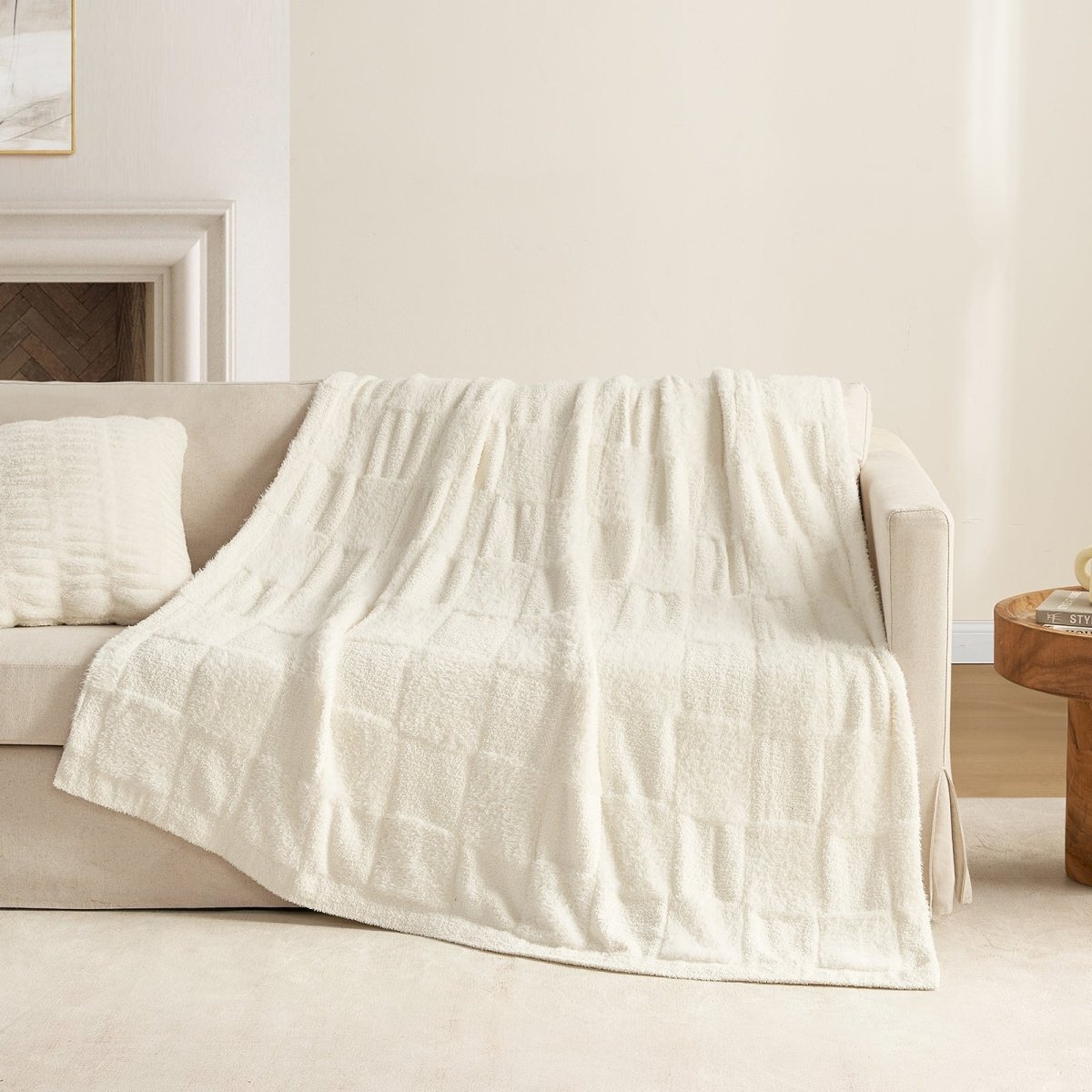 Checkered Faux Fur Feather Yarn Throw Blanket in Ivory draped over a sofa, highlighting its soft feel and subtle pattern. #color_Ivory