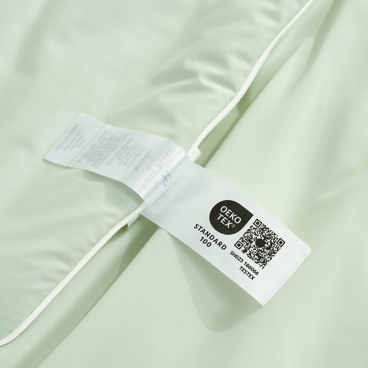 Close up of OEKO-TEX certified Cozy Bliss cooling comforter, breathable and soft, ensuring quality and safety.#Color_Light Mint Green/Cream