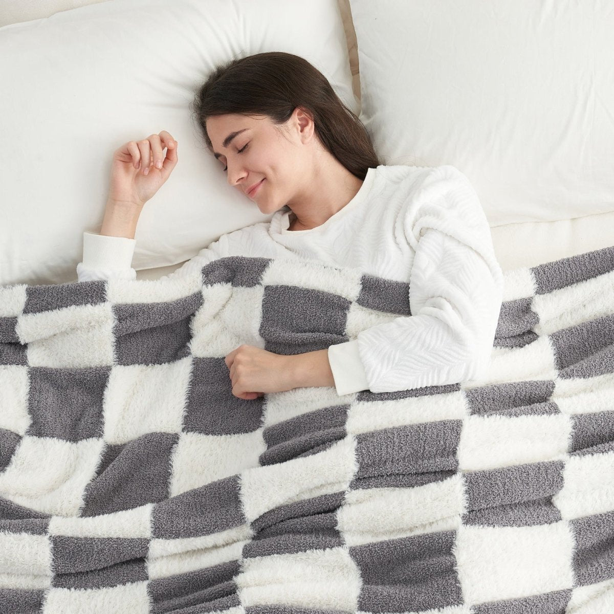 Woman sleeping under a Checkered Faux Fur Feather Yarn Throw Blanket in Grey & White, providing cozy warmth. #color_Grey & White