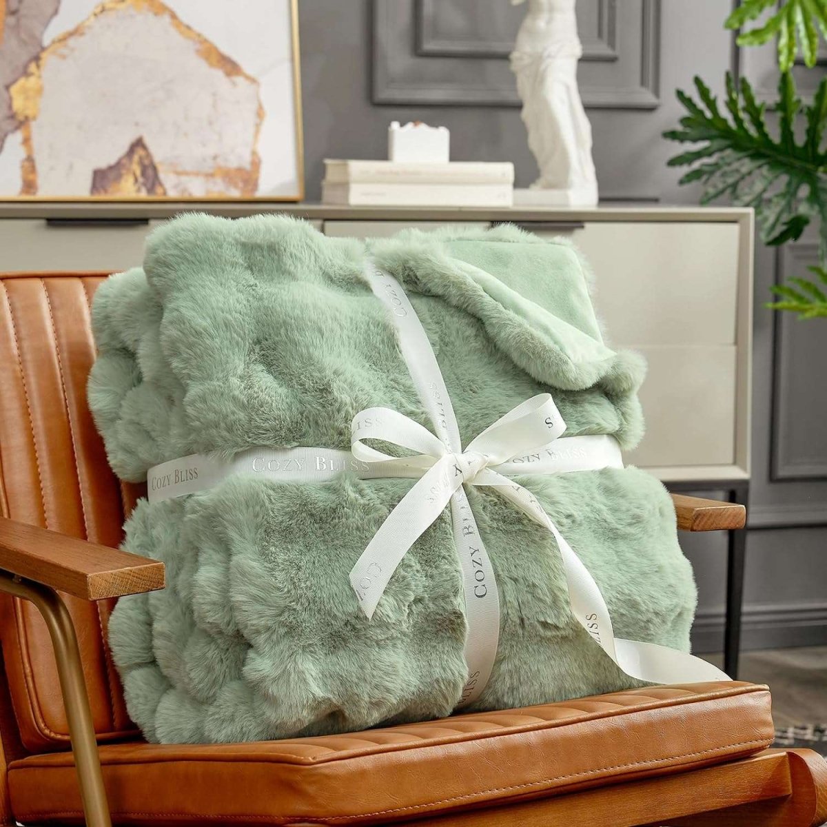 Fluffy sage green blanket with a bow on an armchair. #color_Sage Green