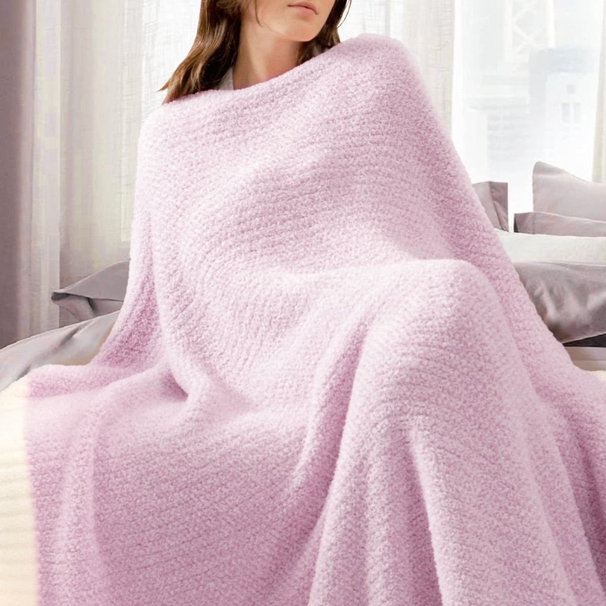 Woman wrapped in a Heather Feather Yarn Throw Blanket in Purple, relaxing on a bed. #color_Purple